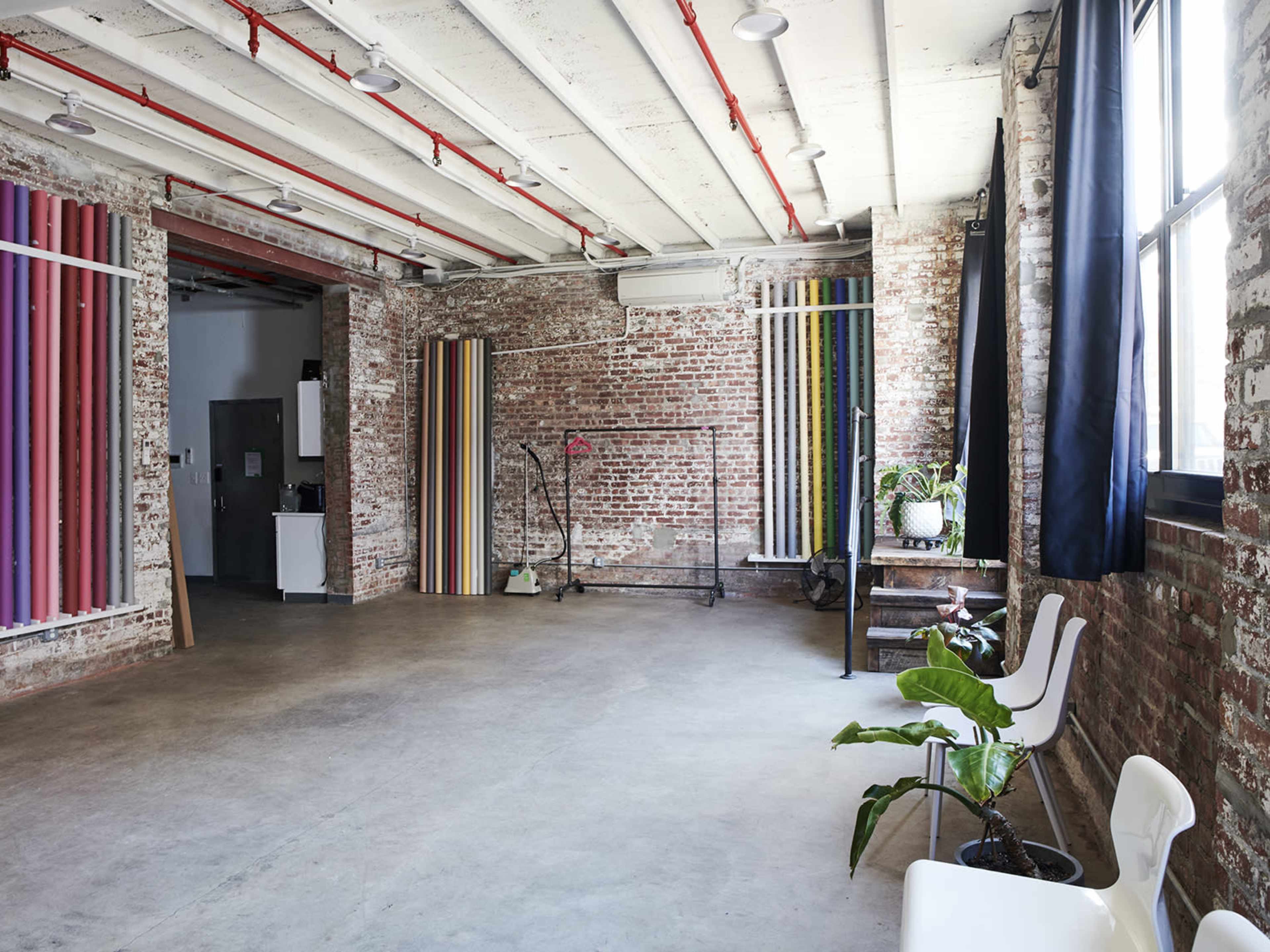An industrial-style interior space with exposed brick walls, concrete flooring, and colorful vertical panels on display.