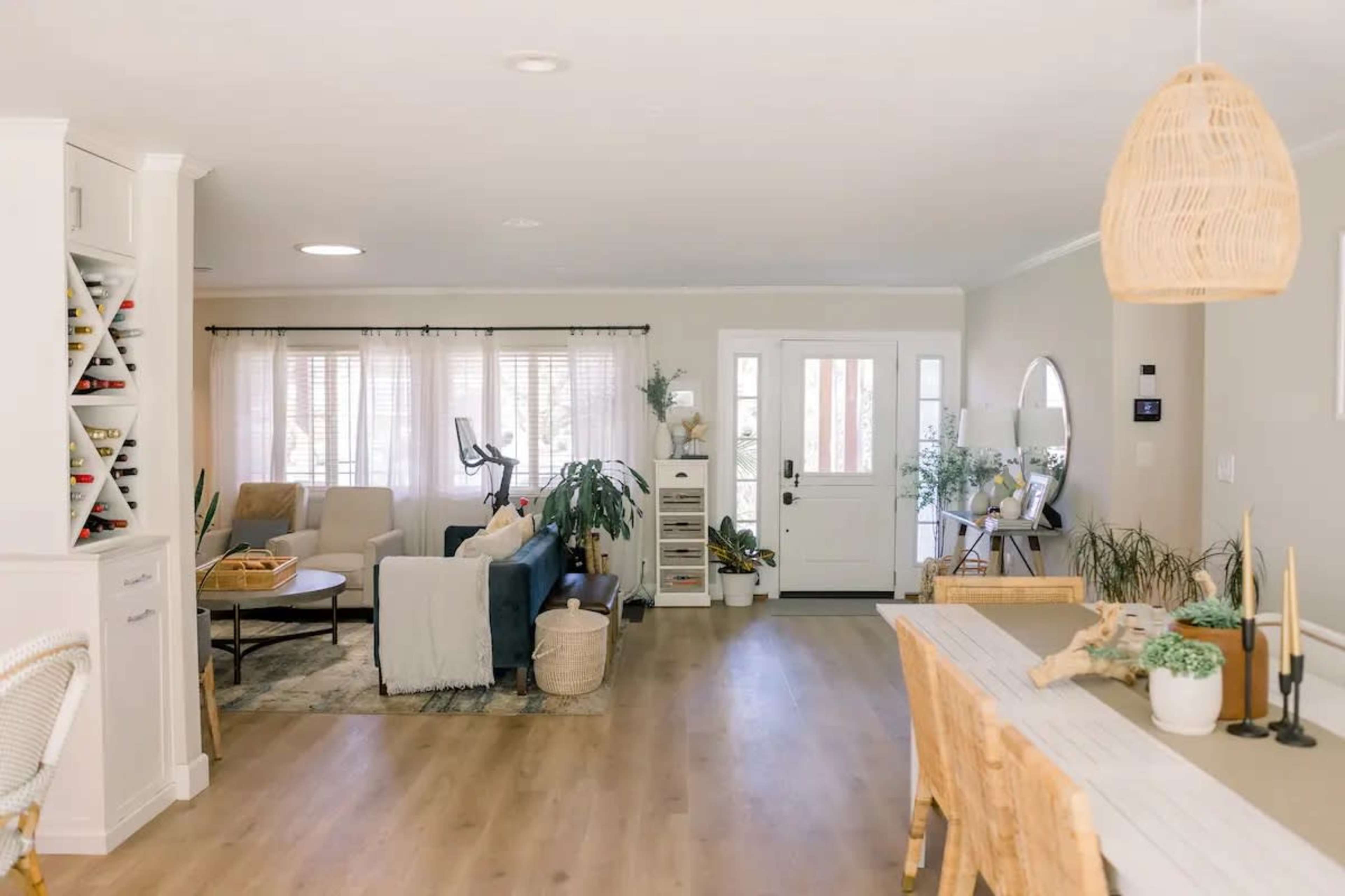 A bright living room with a blue sofa, a dining table, and large windows letting in natural light.
