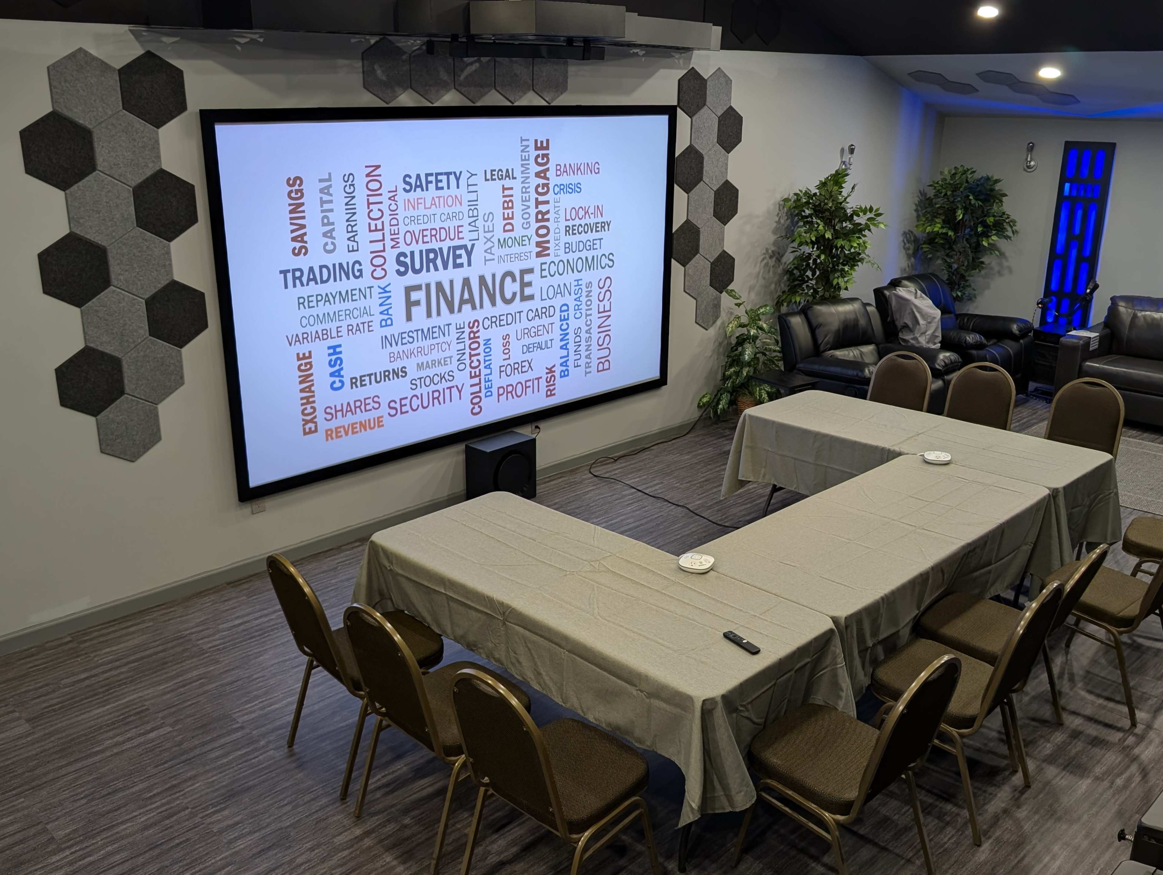 A modern conference room features a large screen with a word cloud related to finance, surrounded by tables and chairs.