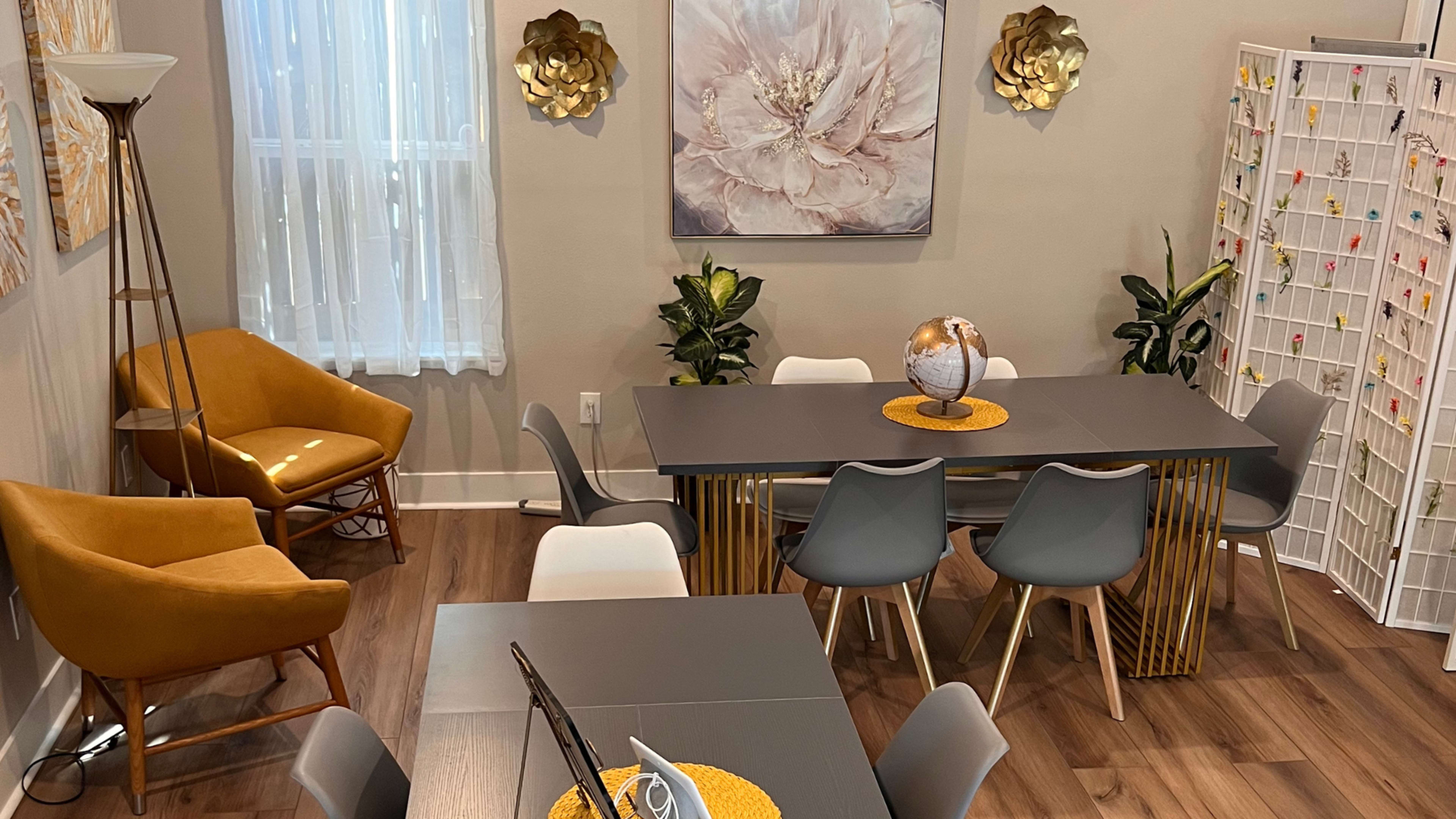A modern dining area features a large table surrounded by various chairs, a globe centerpiece, and decorative wall art.