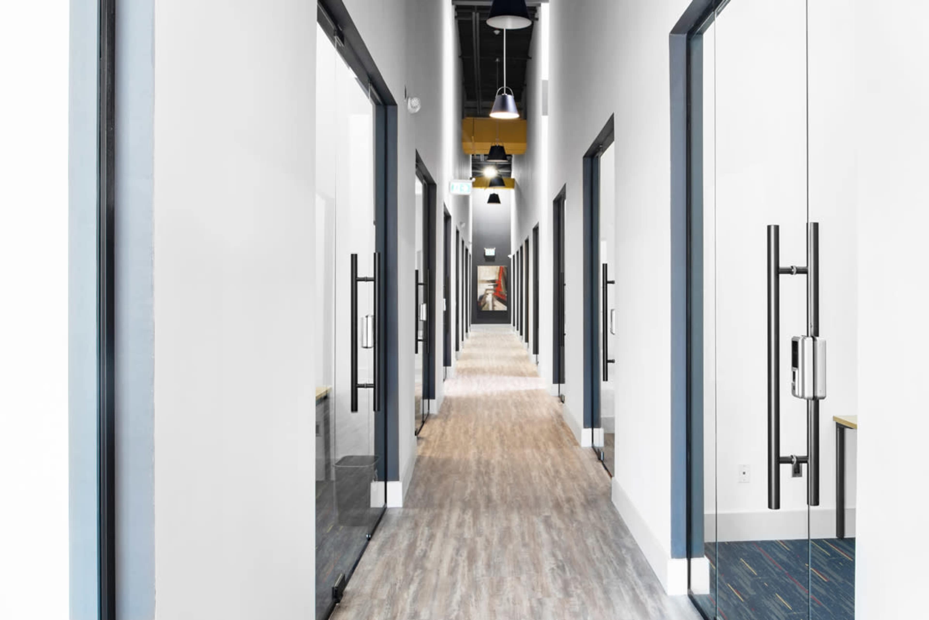A long, narrow corridor lined with doors on either side, leading toward a distant view of the hallway's end.
