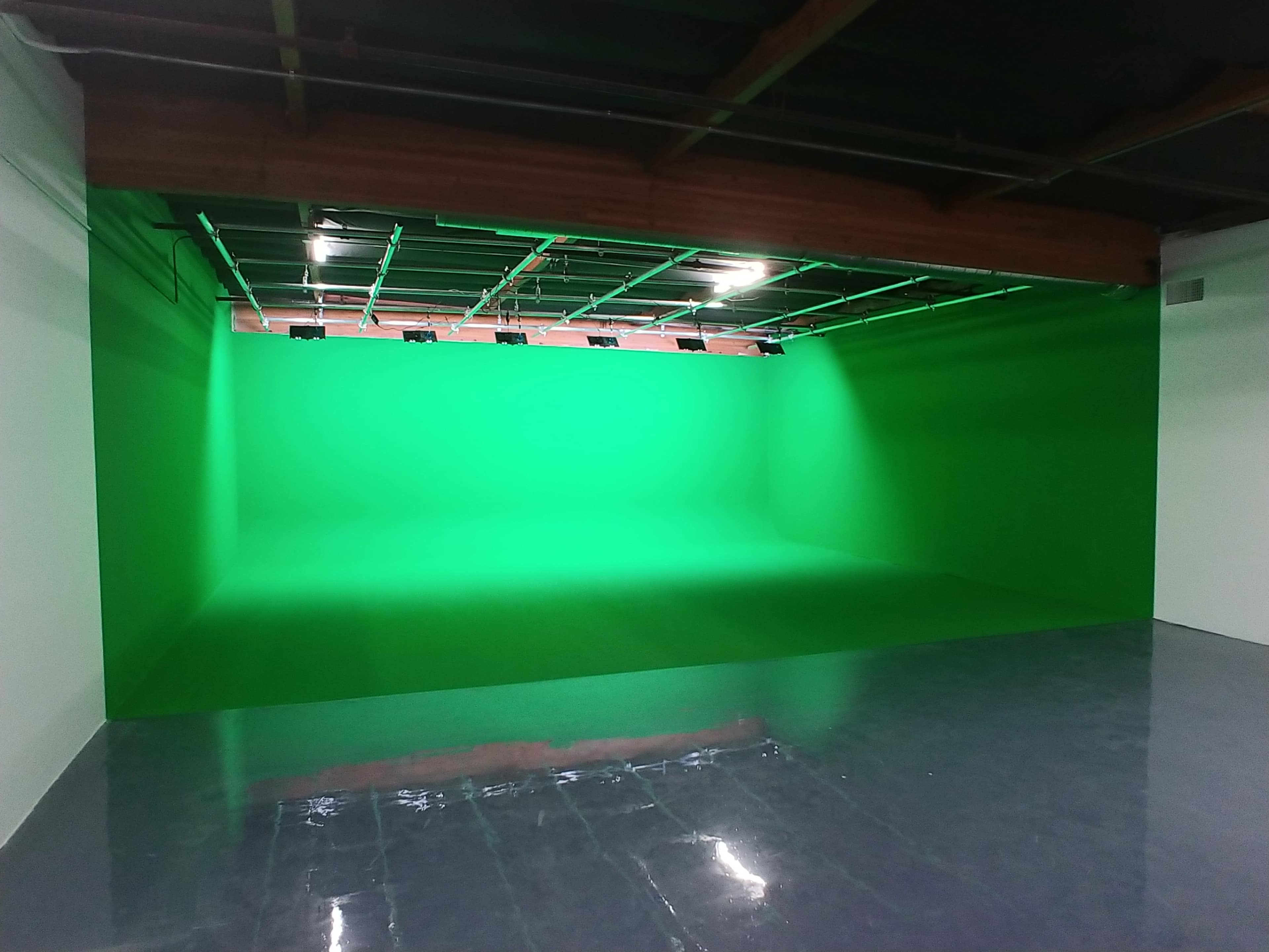The image shows a large room with a bright green backdrop and polished concrete flooring.
