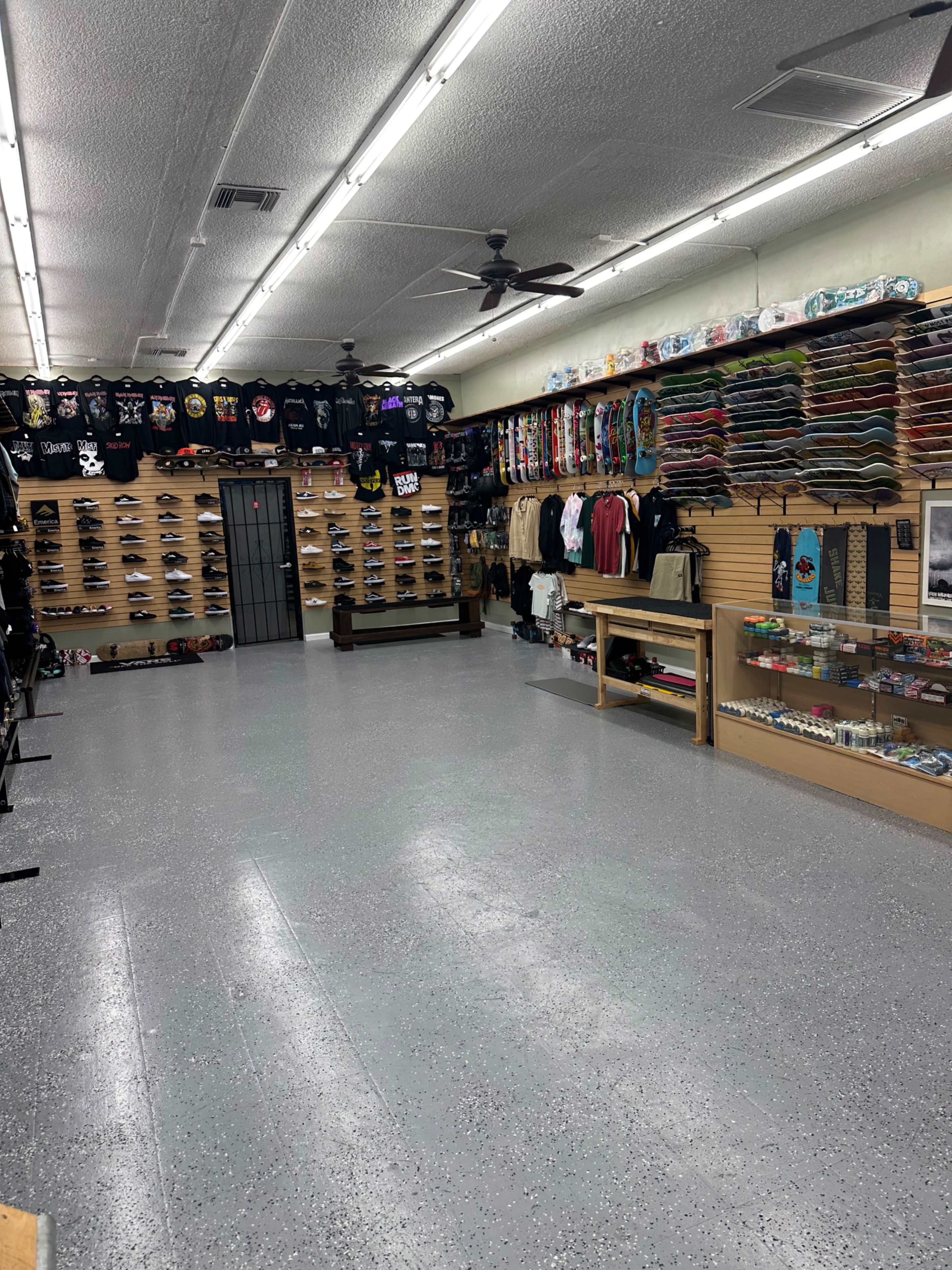 The interior of a retail store featuring a variety of clothing and skateboards displayed on racks along the walls.