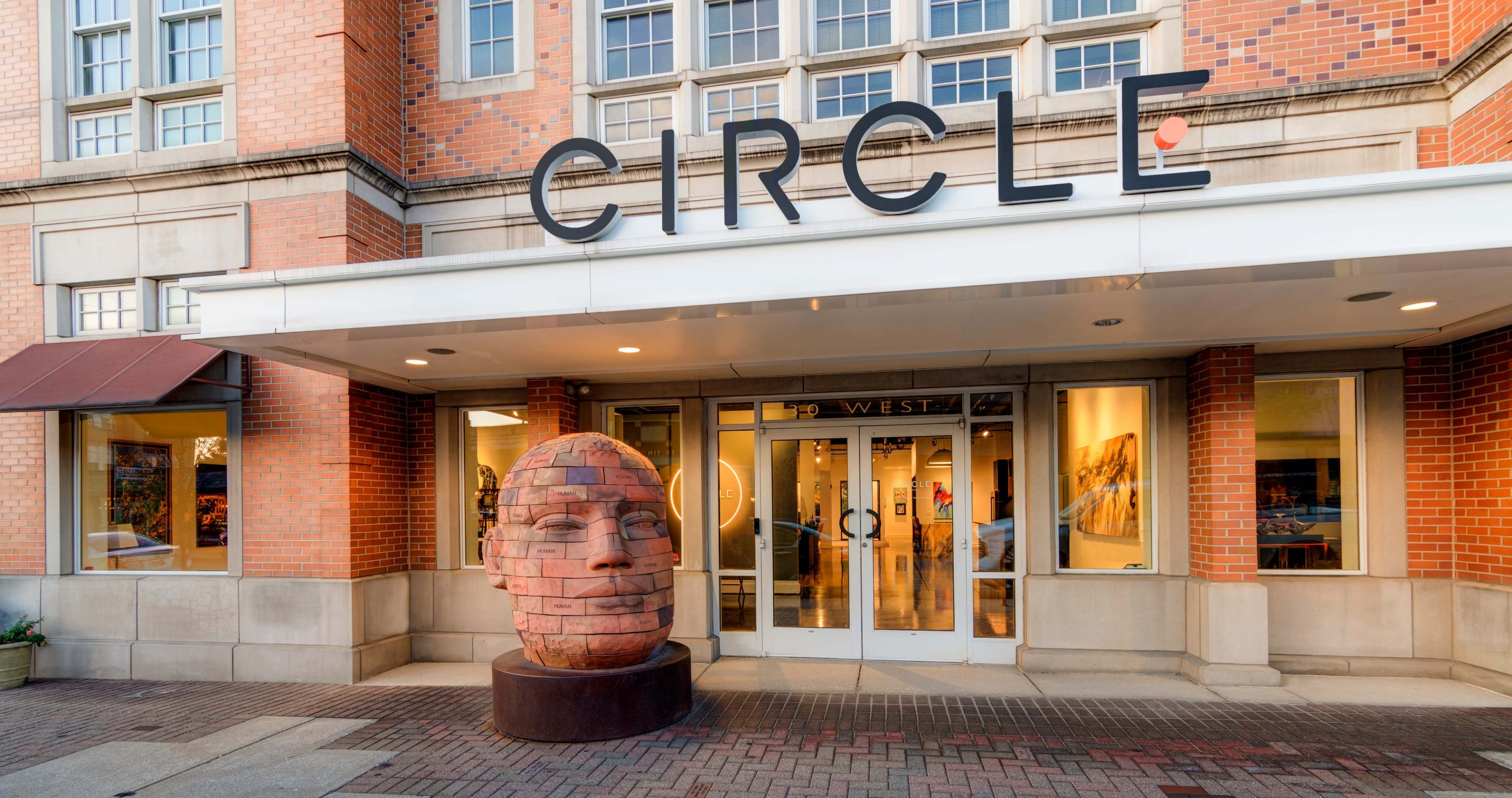 The entrance of a building labeled "CIRCLE" features a large, sculpted head as a centerpiece.