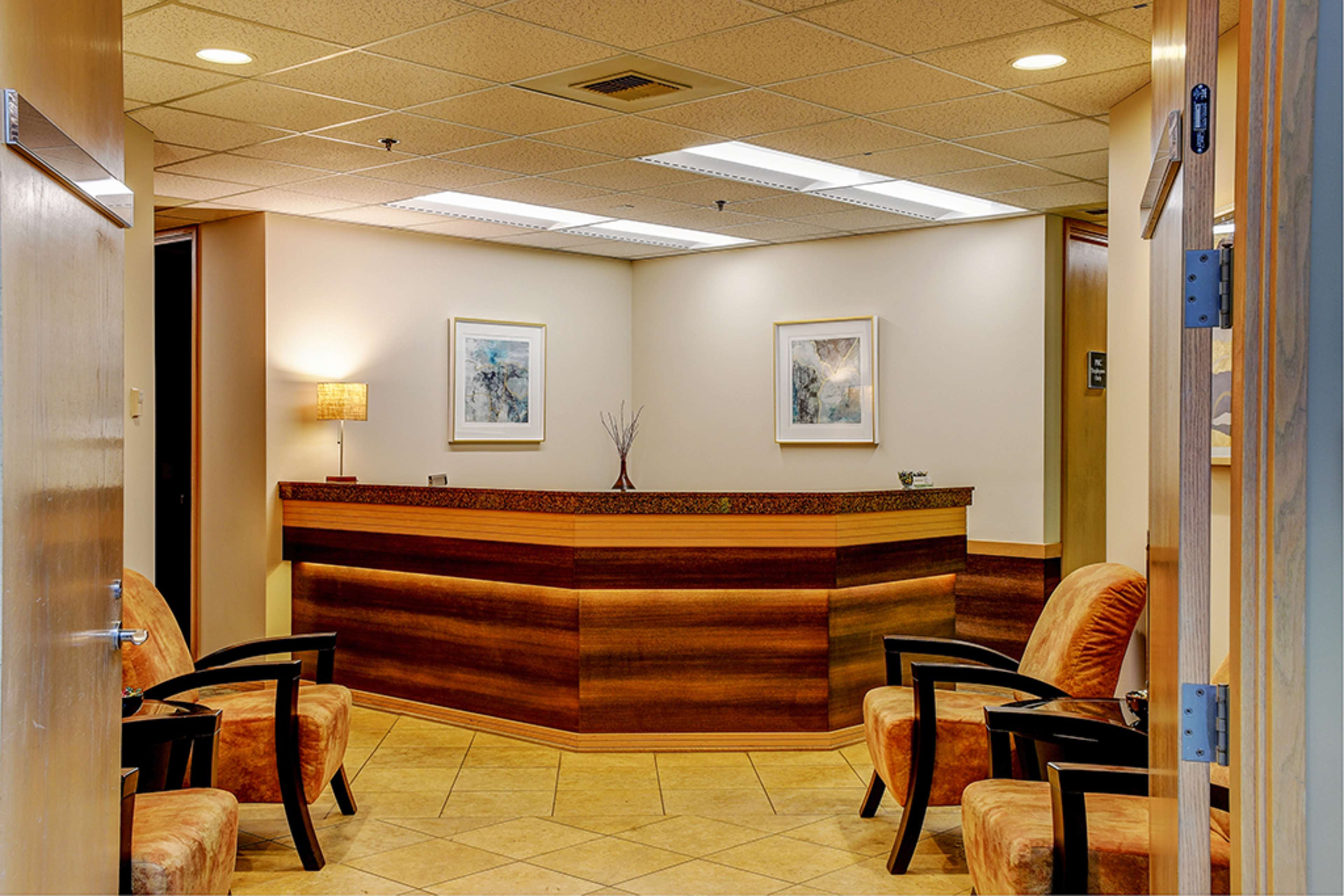 A reception area with a curved front desk and two chairs in the foreground.