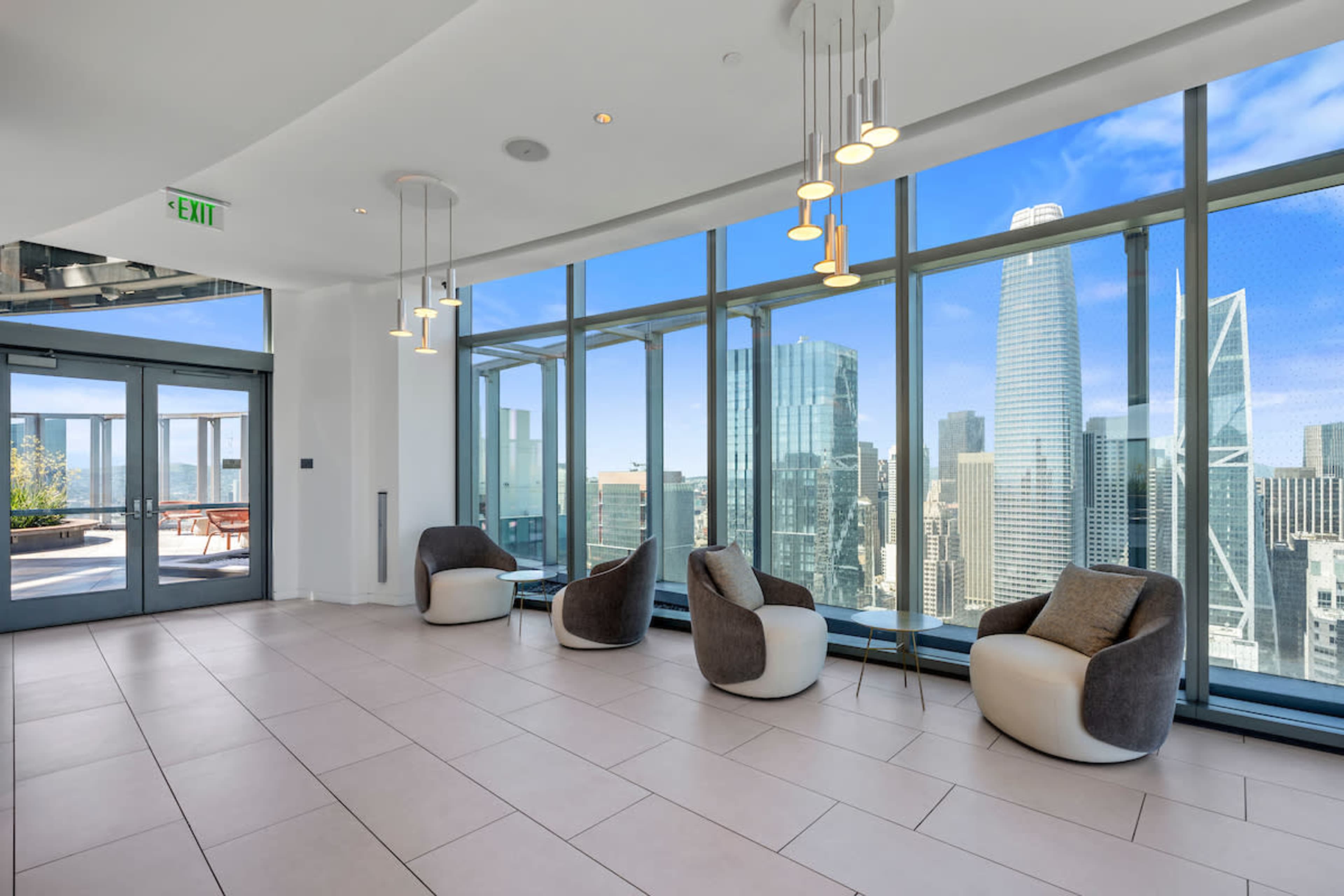 The image shows a modern lobby space with large windows offering a view of a city skyline, featuring several contemporary chairs arranged on a tiled floor.