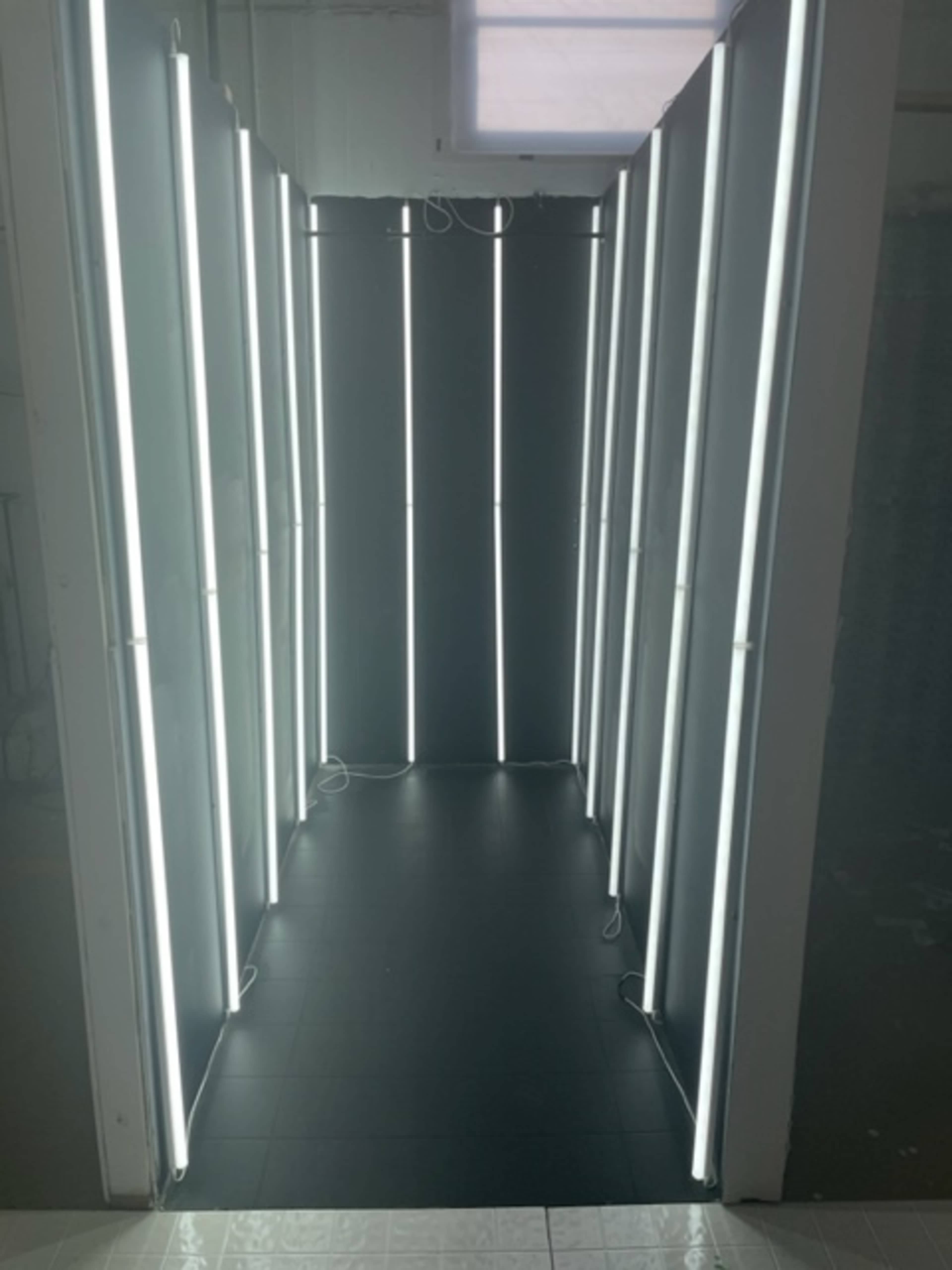 A narrow corridor lined with vertical LED light panels against a dark backdrop.