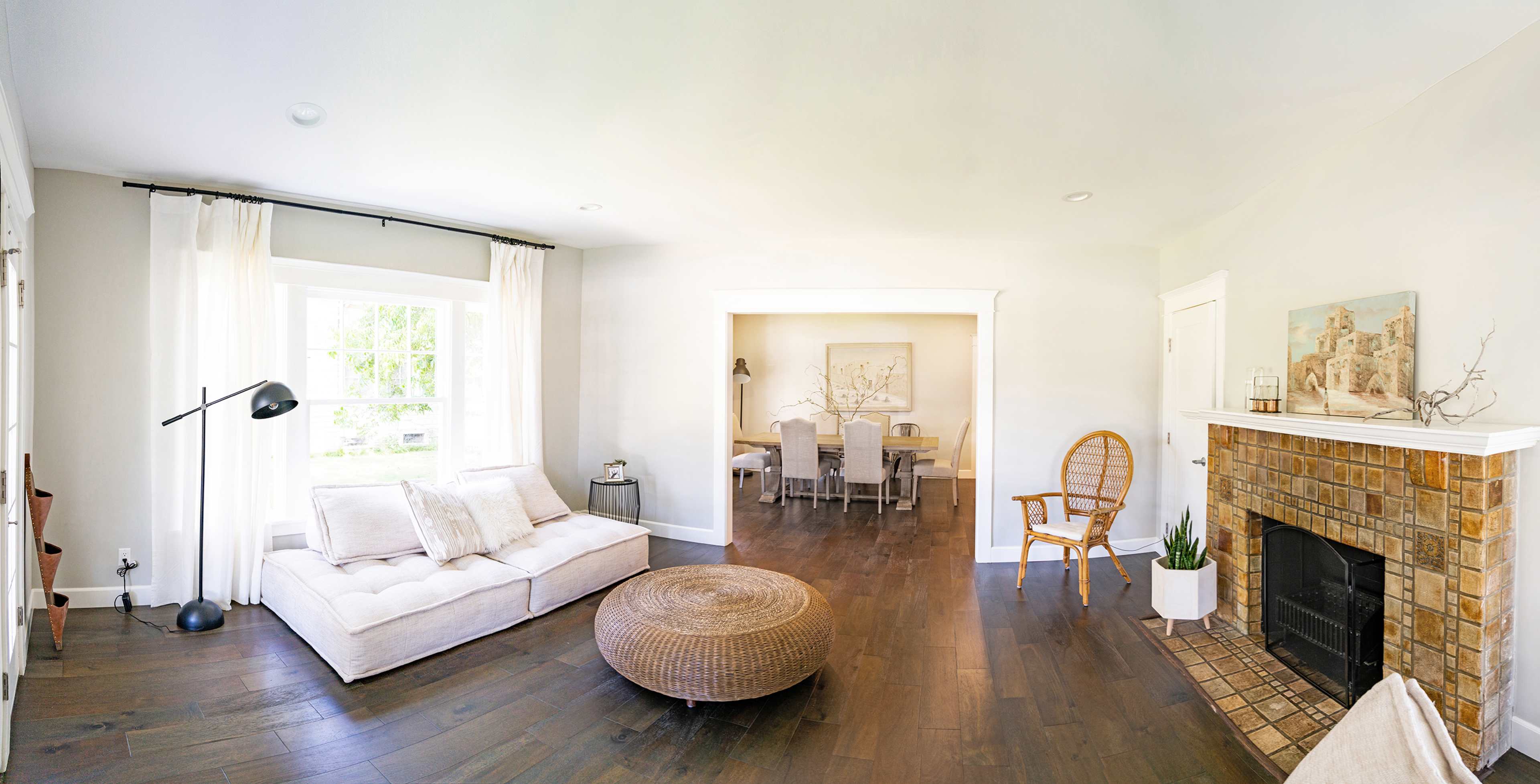 A spacious living room with a light-colored sofa, a round coffee table, and a dining area visible in the background.