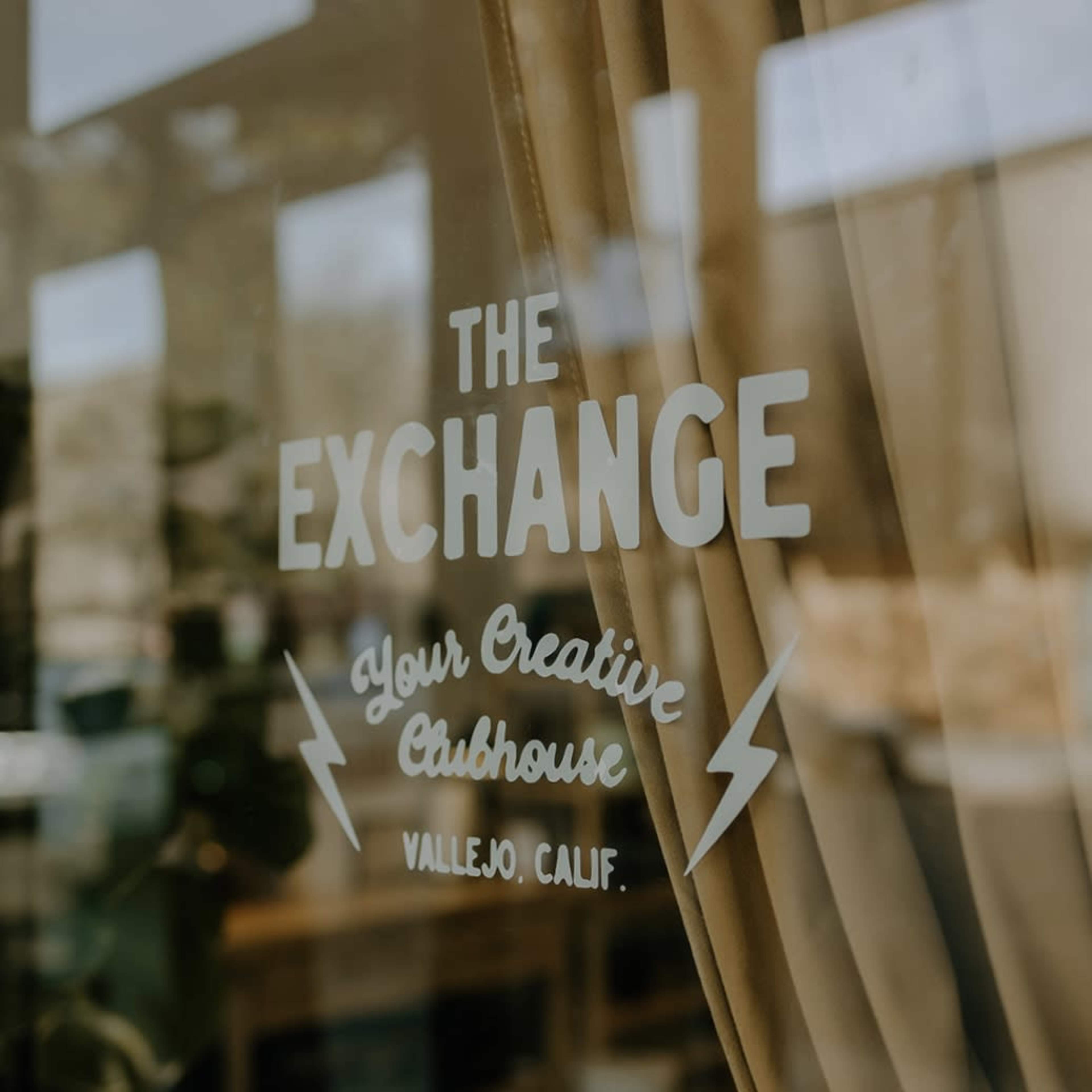 The image shows a window with a sign that reads "The Exchange" and "Your Creative Clubhouse" in Vallejo, California.