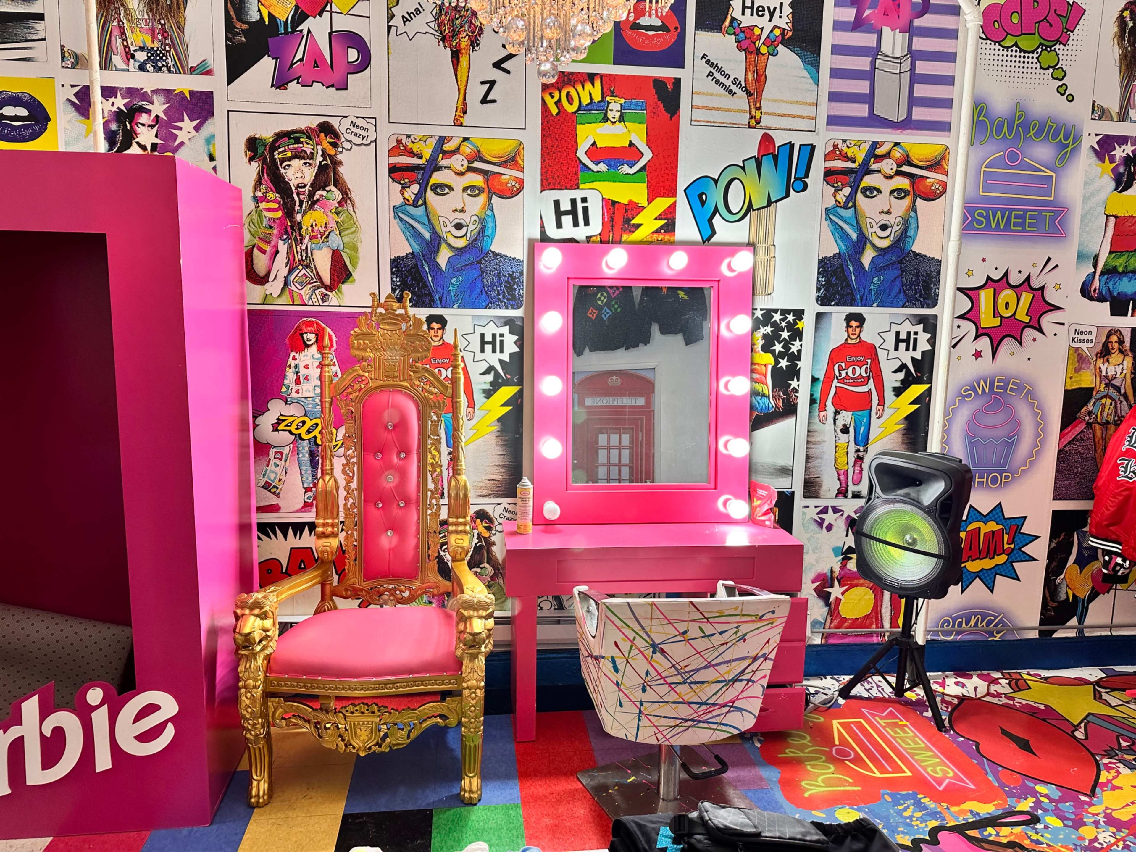 The scene features a vibrant room with a pink throne, a lighted vanity mirror, and colorful pop art posters on the walls.