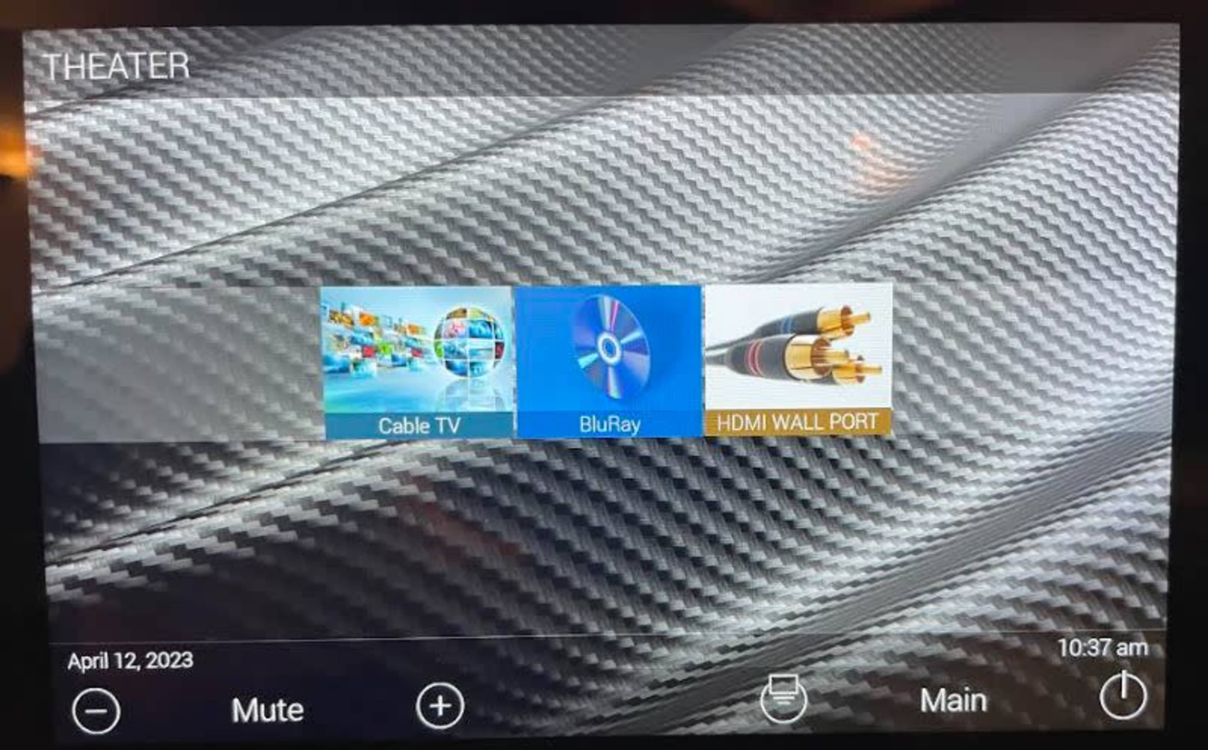 A display screen with options for Cable TV, BluRay, and an HDMI wall port, set against a textured carbon fiber background.