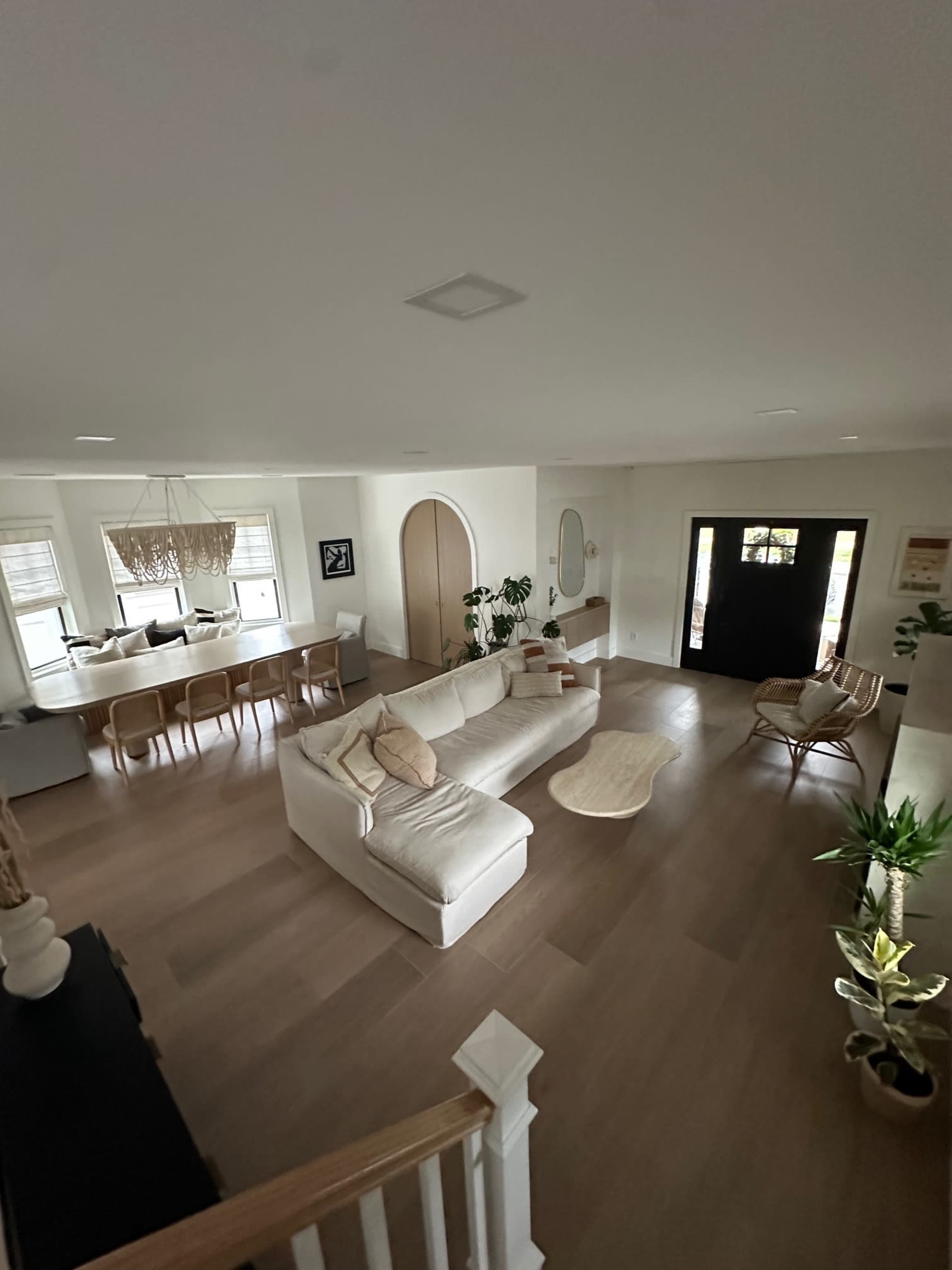 The image shows a spacious living room with a large sectional sofa, a coffee table, and a dining area with a visible kitchen in the background.