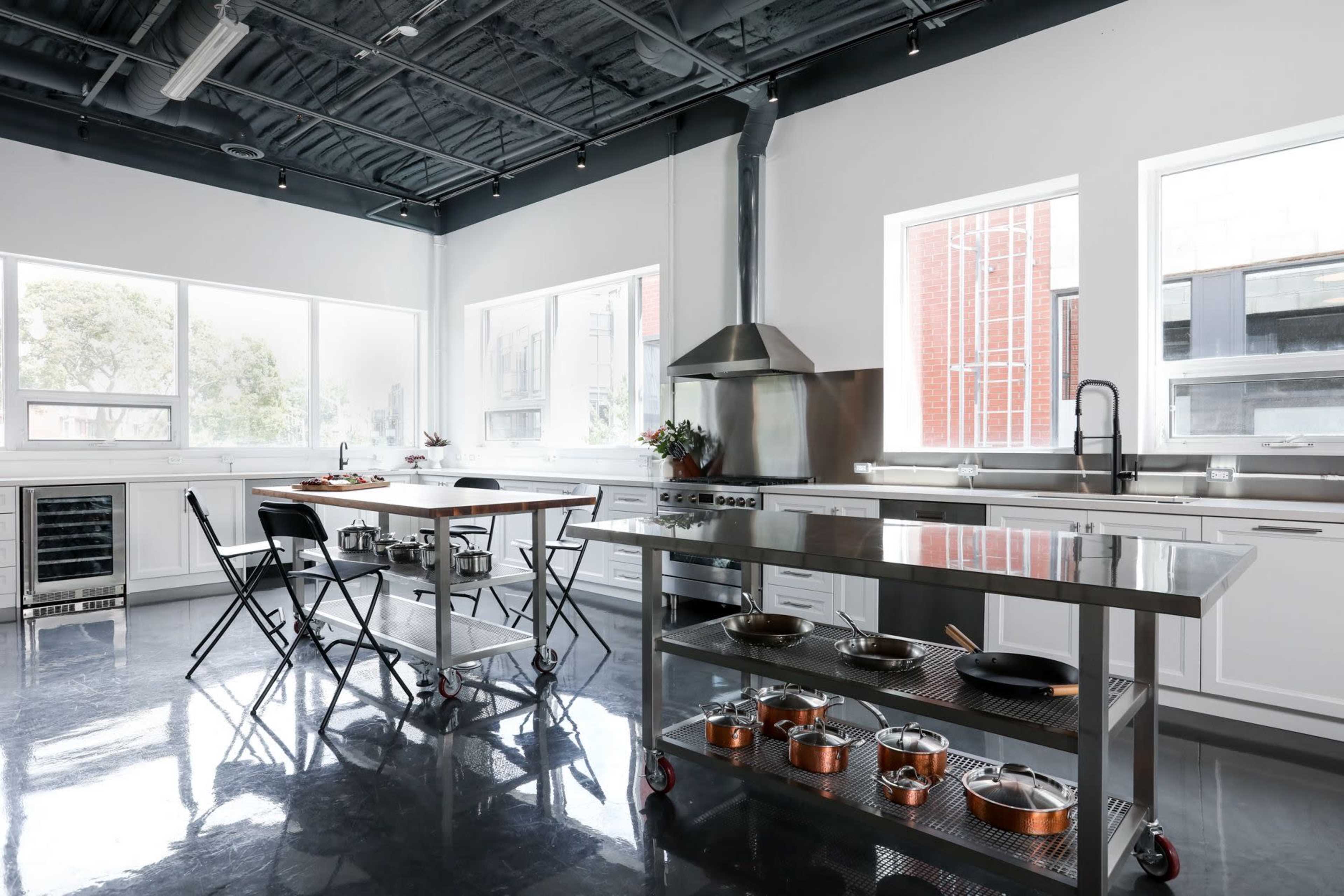 A modern kitchen featuring stainless steel appliances, a central island with seating, and large windows allowing natural light to enter.
