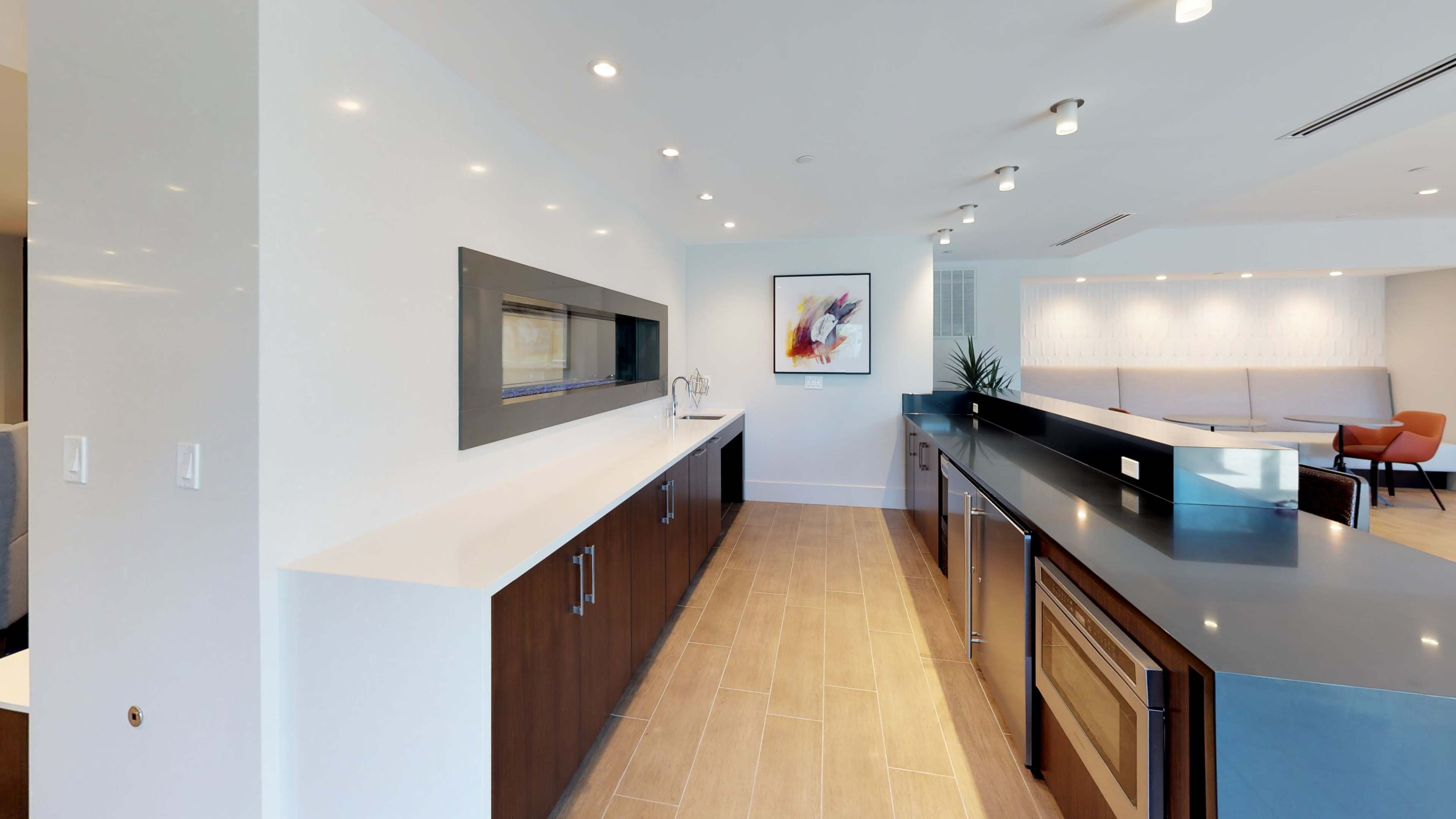 A modern kitchen with dark wood cabinetry, a white countertop, and appliances integrated into a sleek black island.