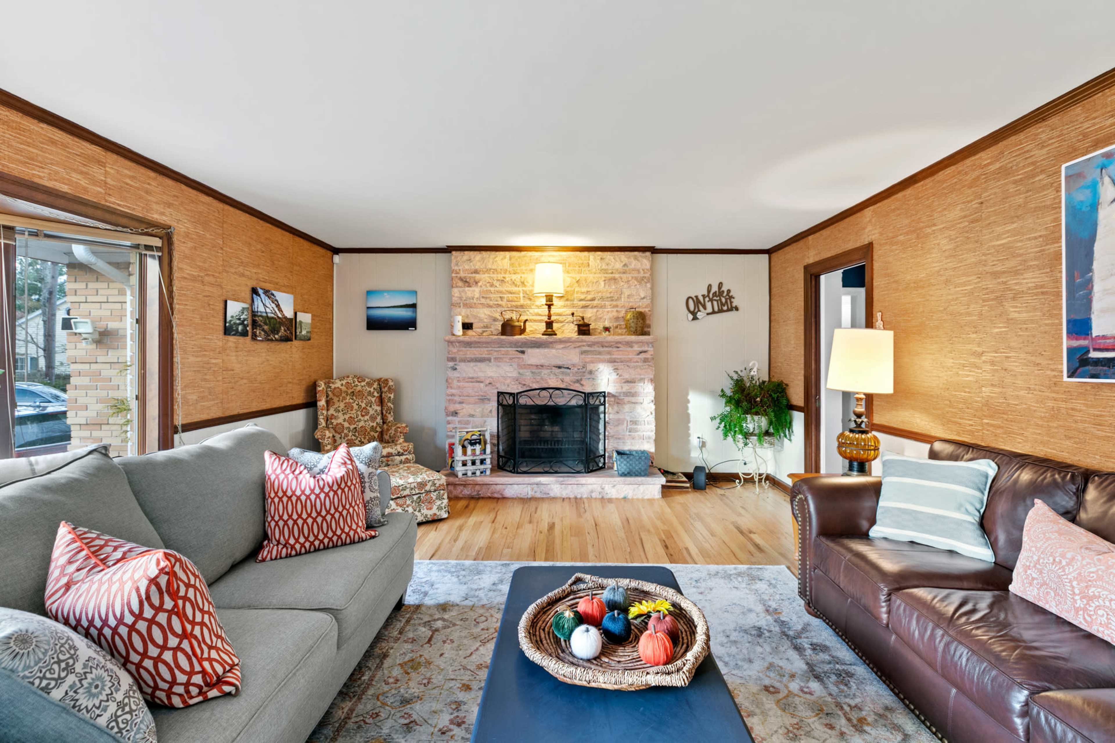 A cozy living room features a stone fireplace, two sofas, and decorative elements on a wooden floor.