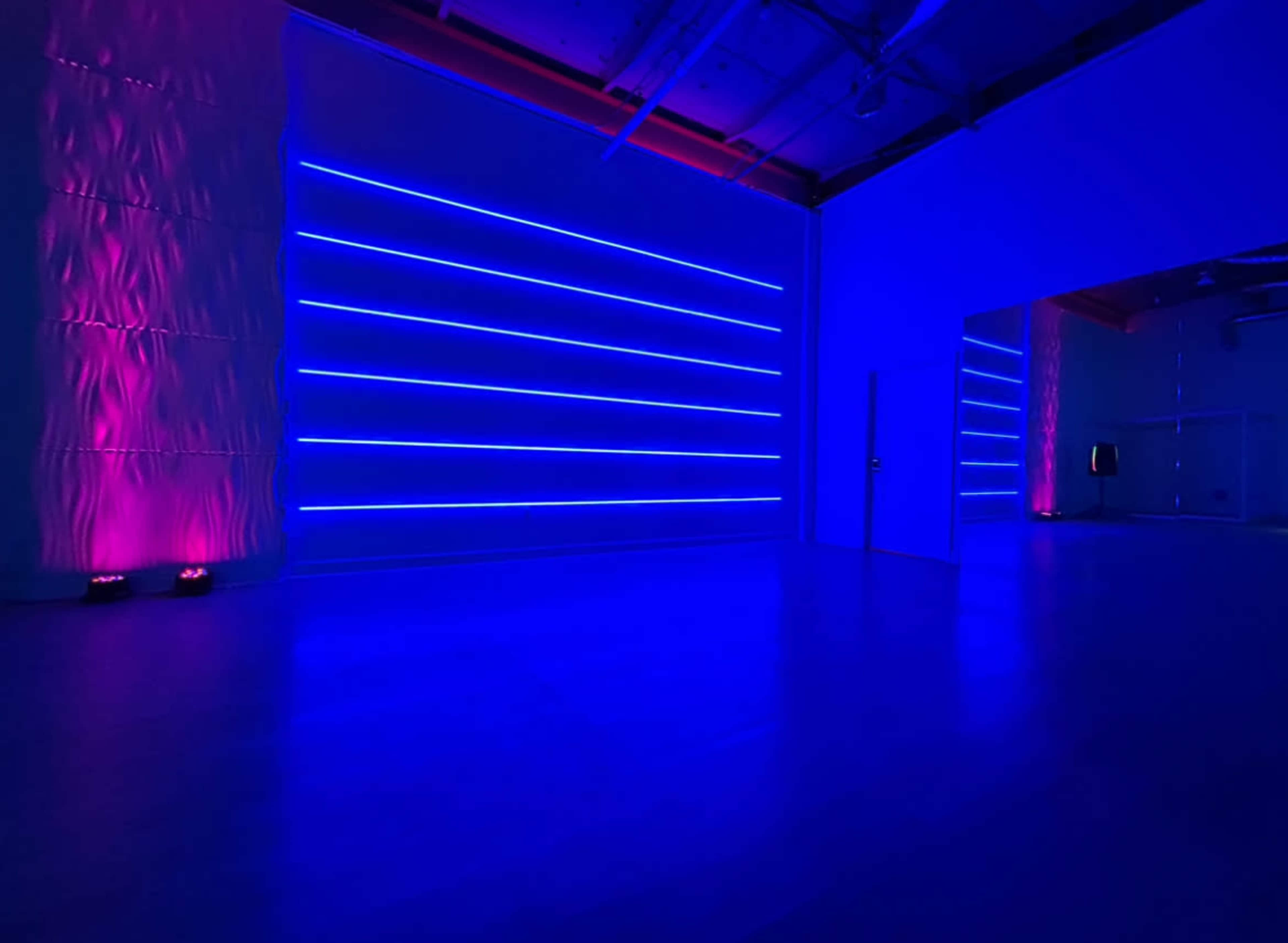 The scene features a dimly lit indoor space with blue and pink LED light strips illuminating the walls.