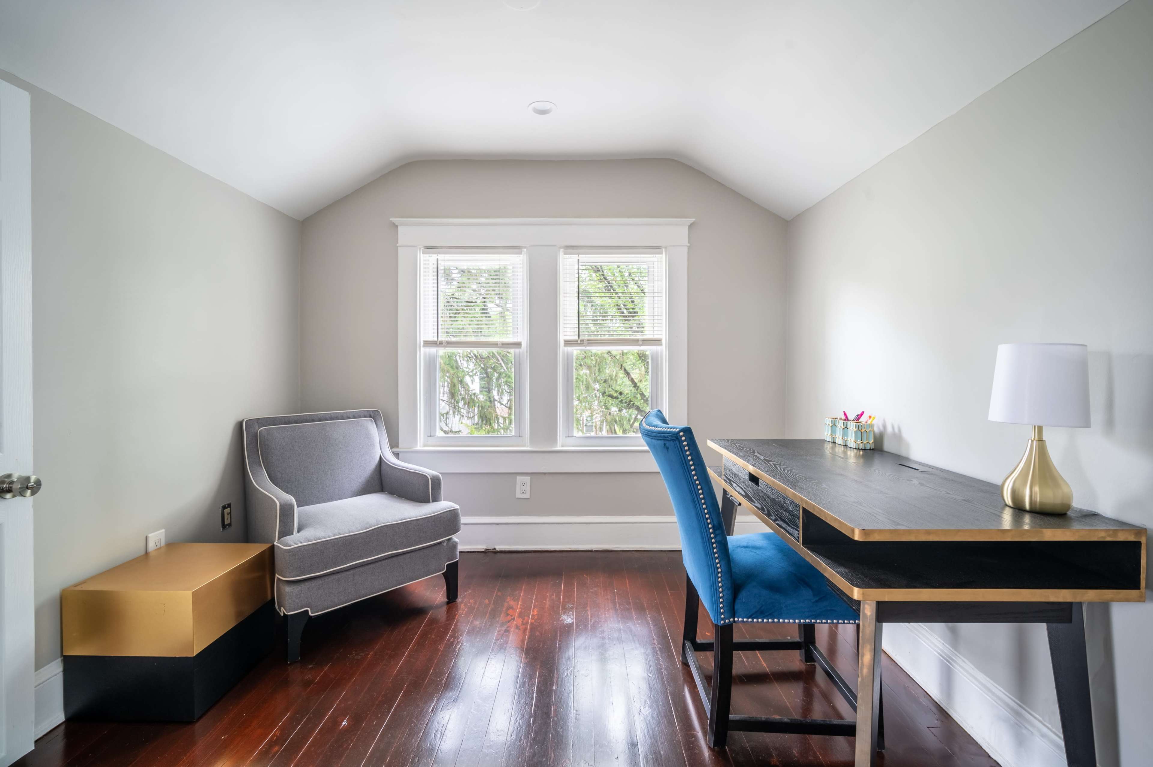 A minimalist home office features a desk, two chairs, and a window with natural light.