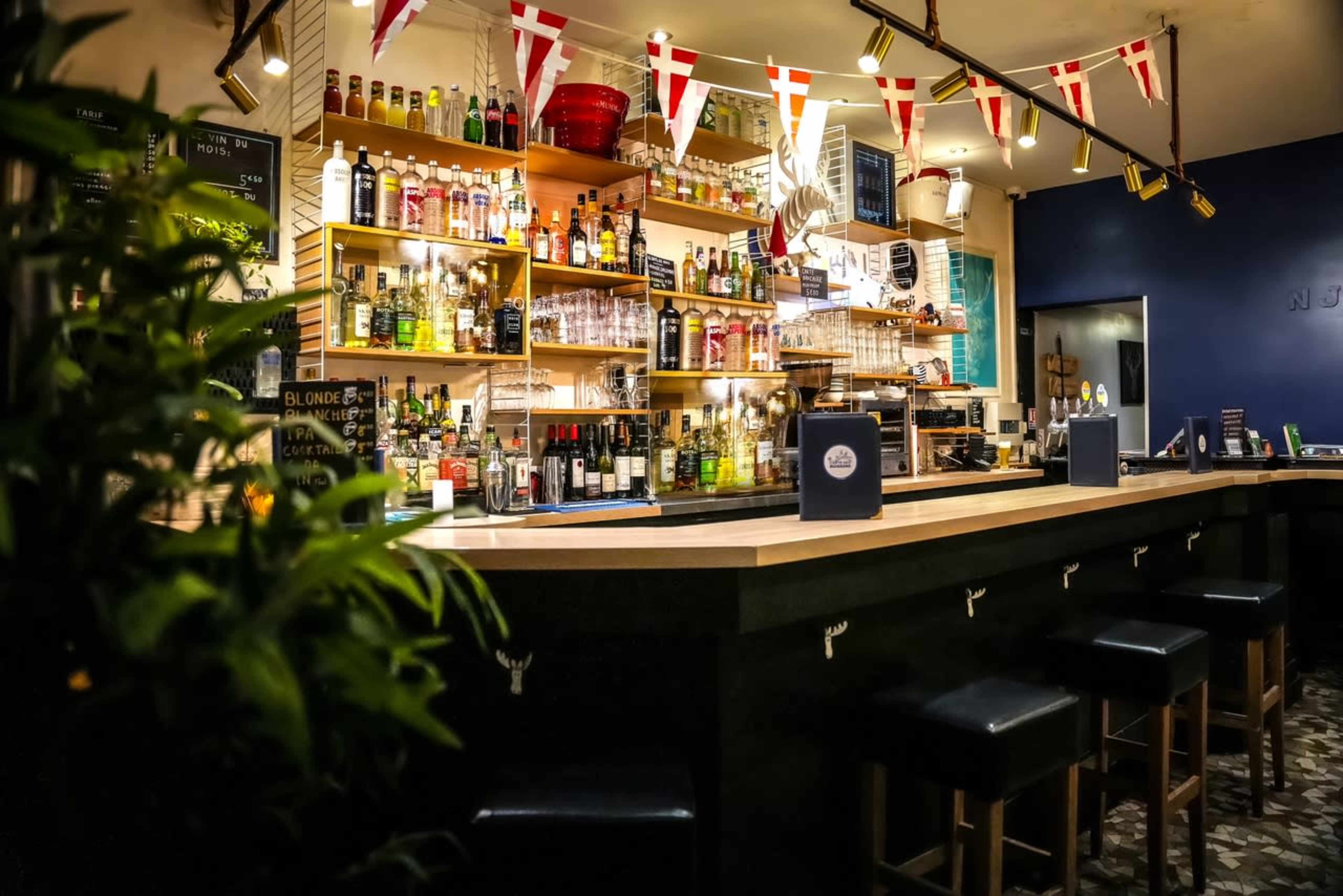 A well-stocked bar with a variety of bottles displayed on shelves and a neatly arranged counter with stools.