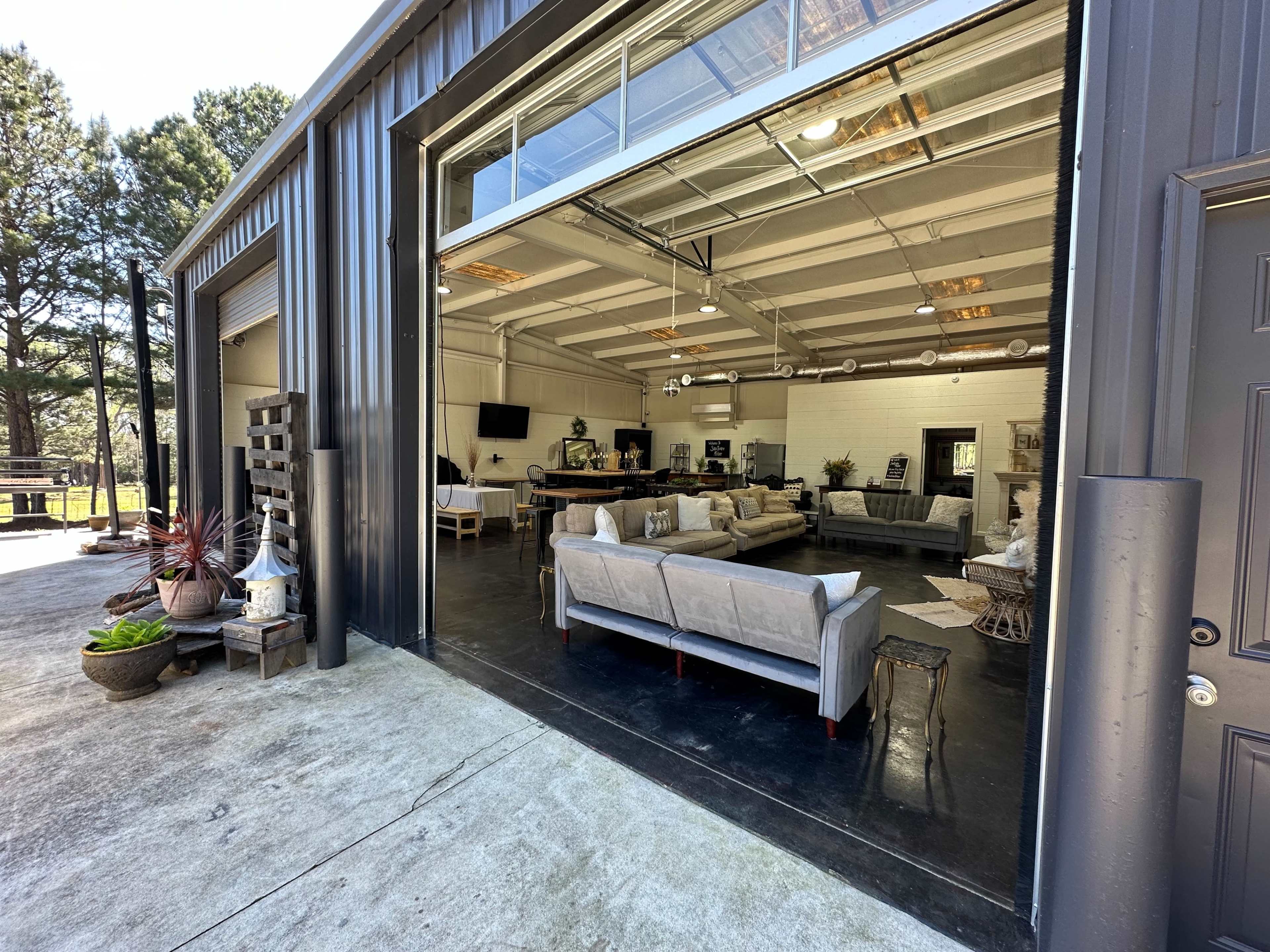 A spacious indoor area with modern furniture is visible through a large open garage door.