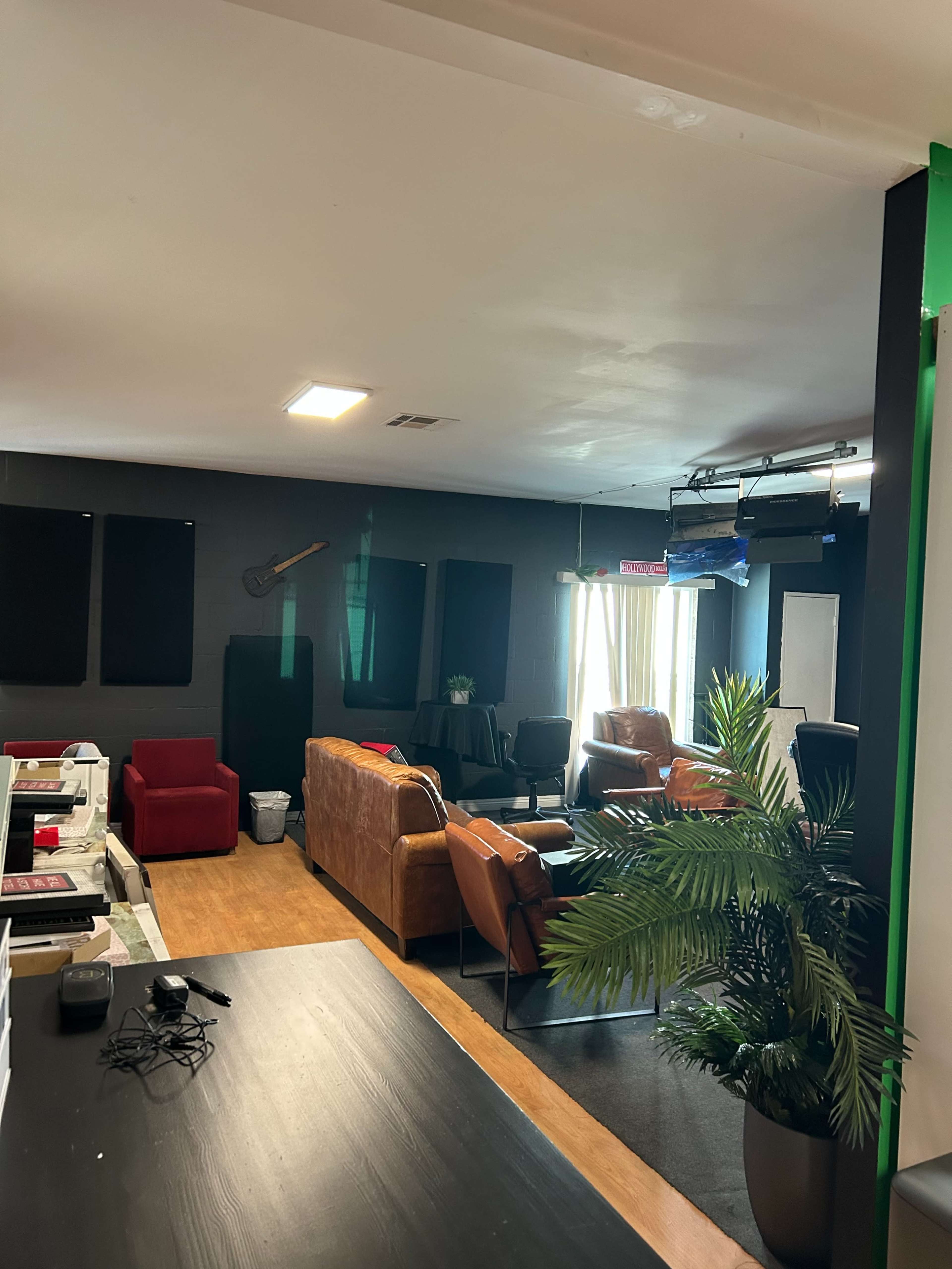 The image shows an interior room with multiple seating areas, a few plants, and equipment in the background.
