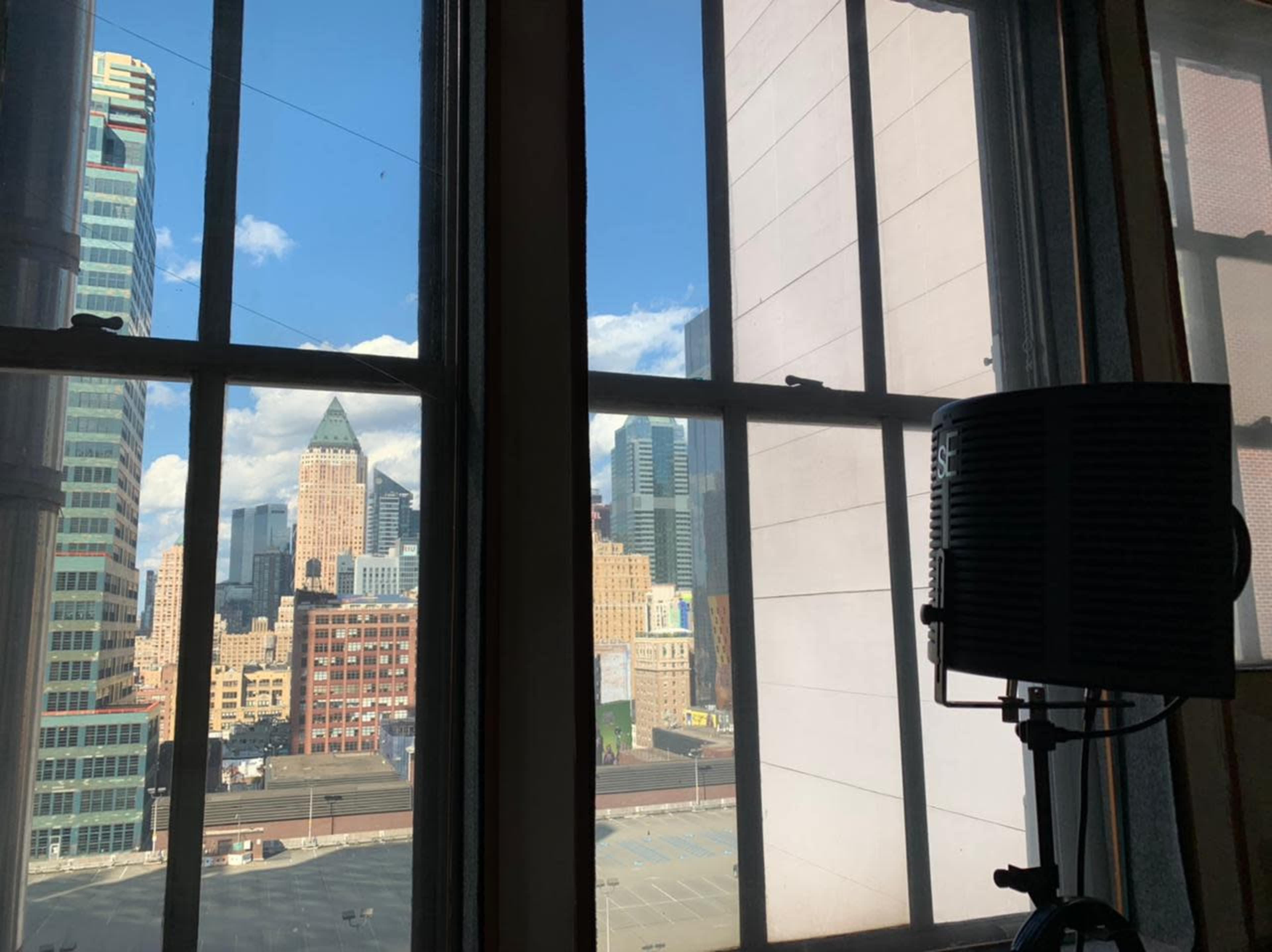 A view of a city skyline through a window, with buildings visible in the background and a speaker beside the window.