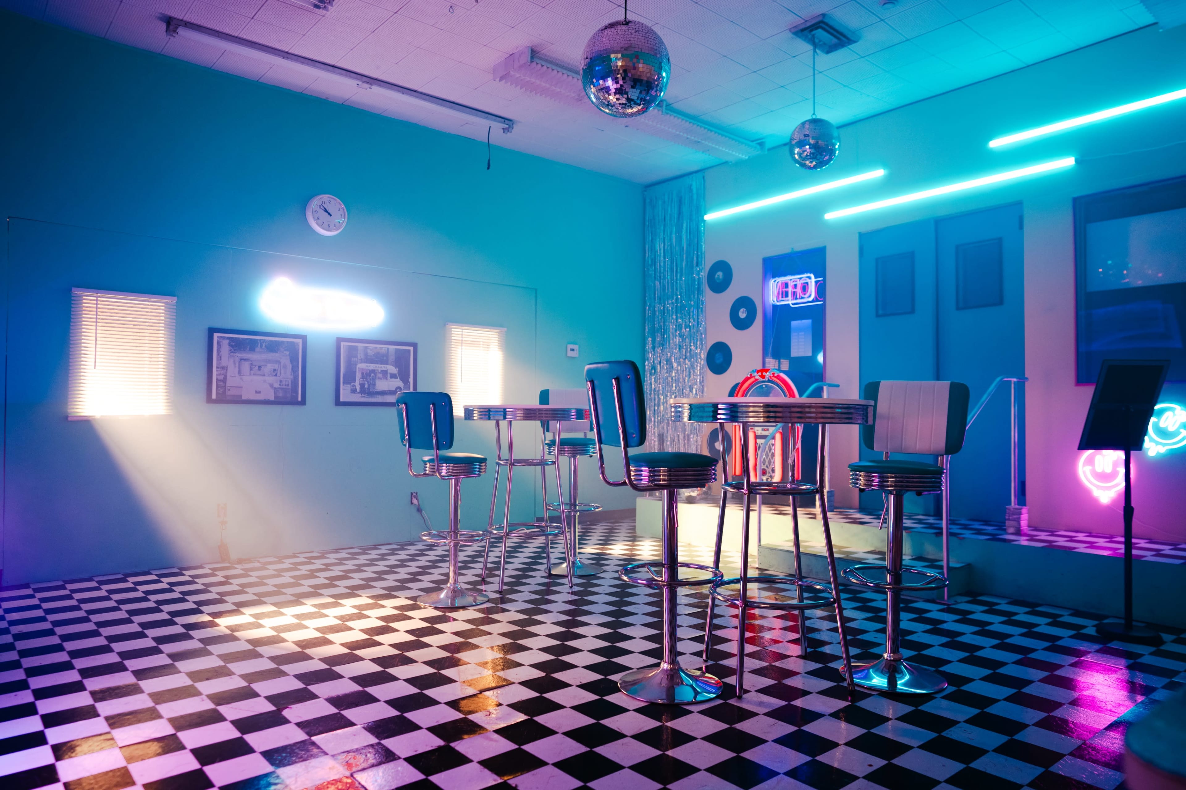A retro-style diner features checkered flooring, chrome stools, and neon lighting.