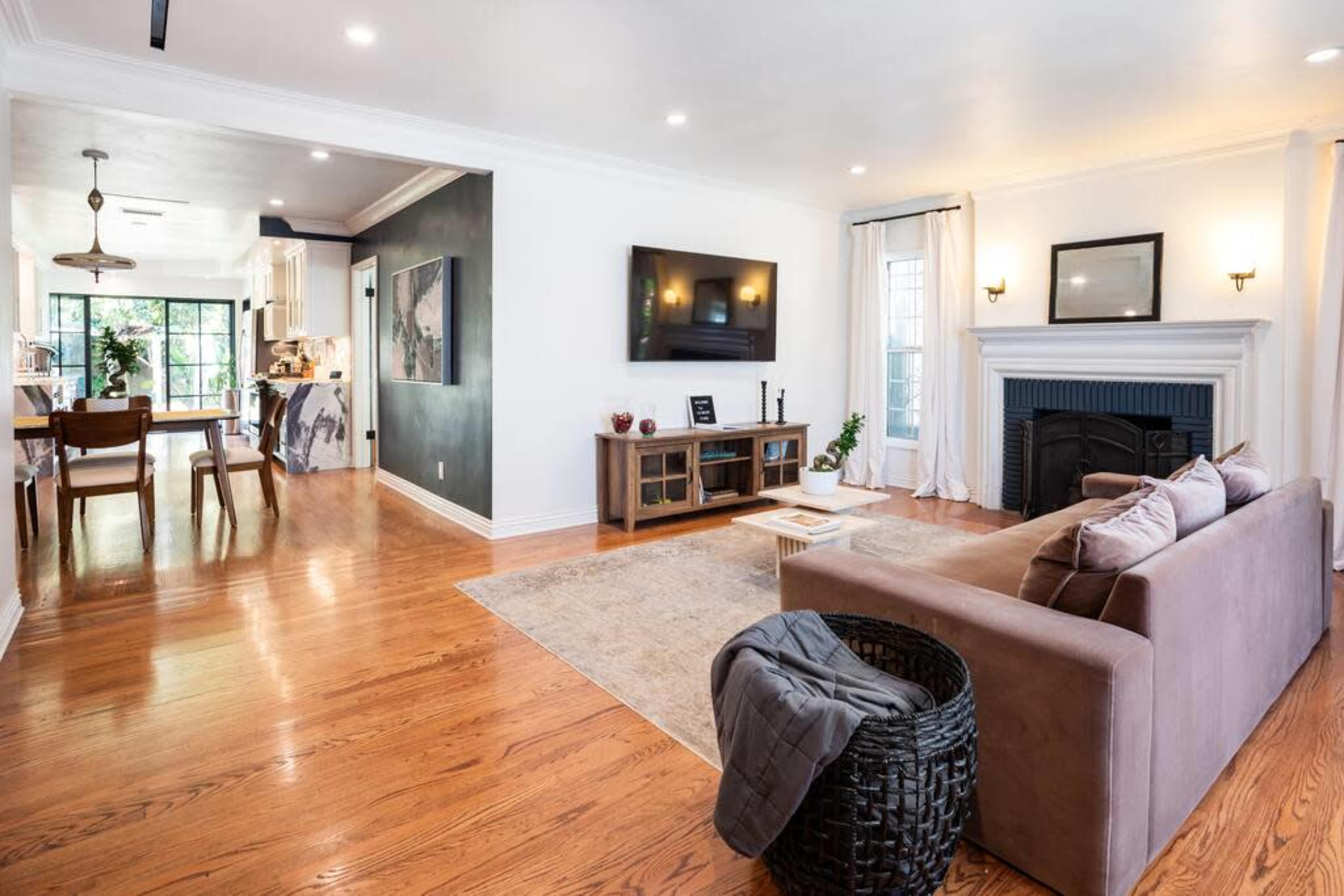 A spacious living room with a brown sofa, a fireplace, and a view into a kitchen with dining area.