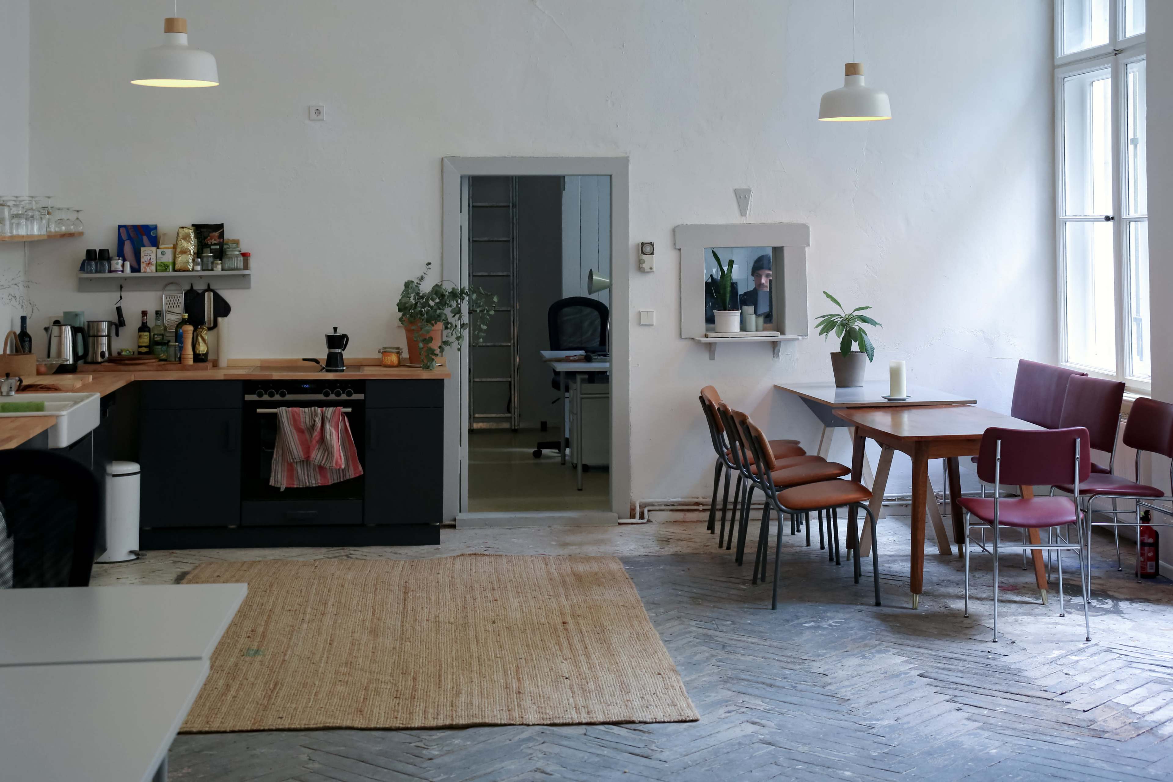 The image shows a spacious kitchen and dining area with a wooden table, chairs, and an open door leading to a separate room.