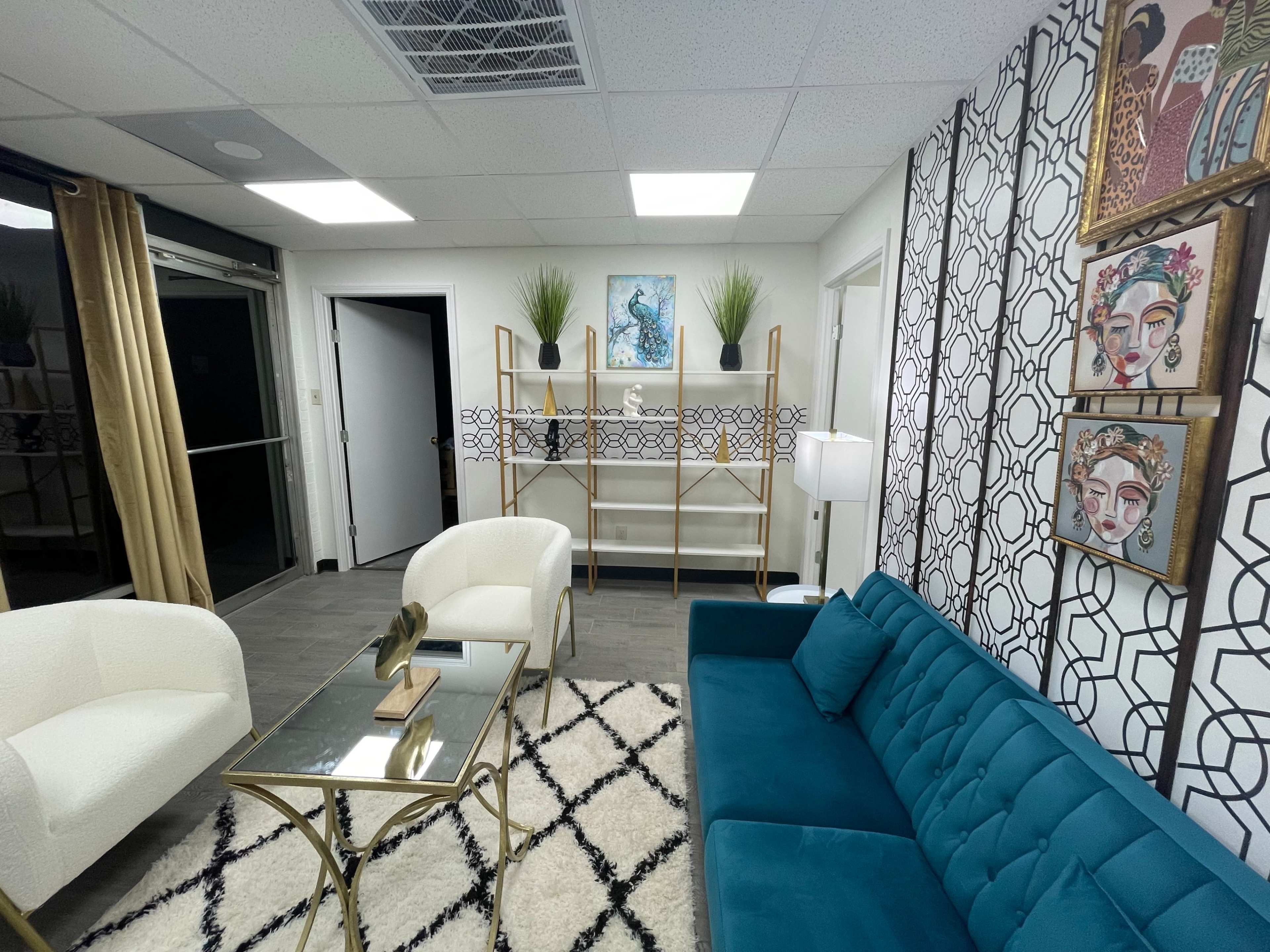 The image shows a modern waiting area with a teal sofa, two white chairs, a glass coffee table, and decorative wall art.