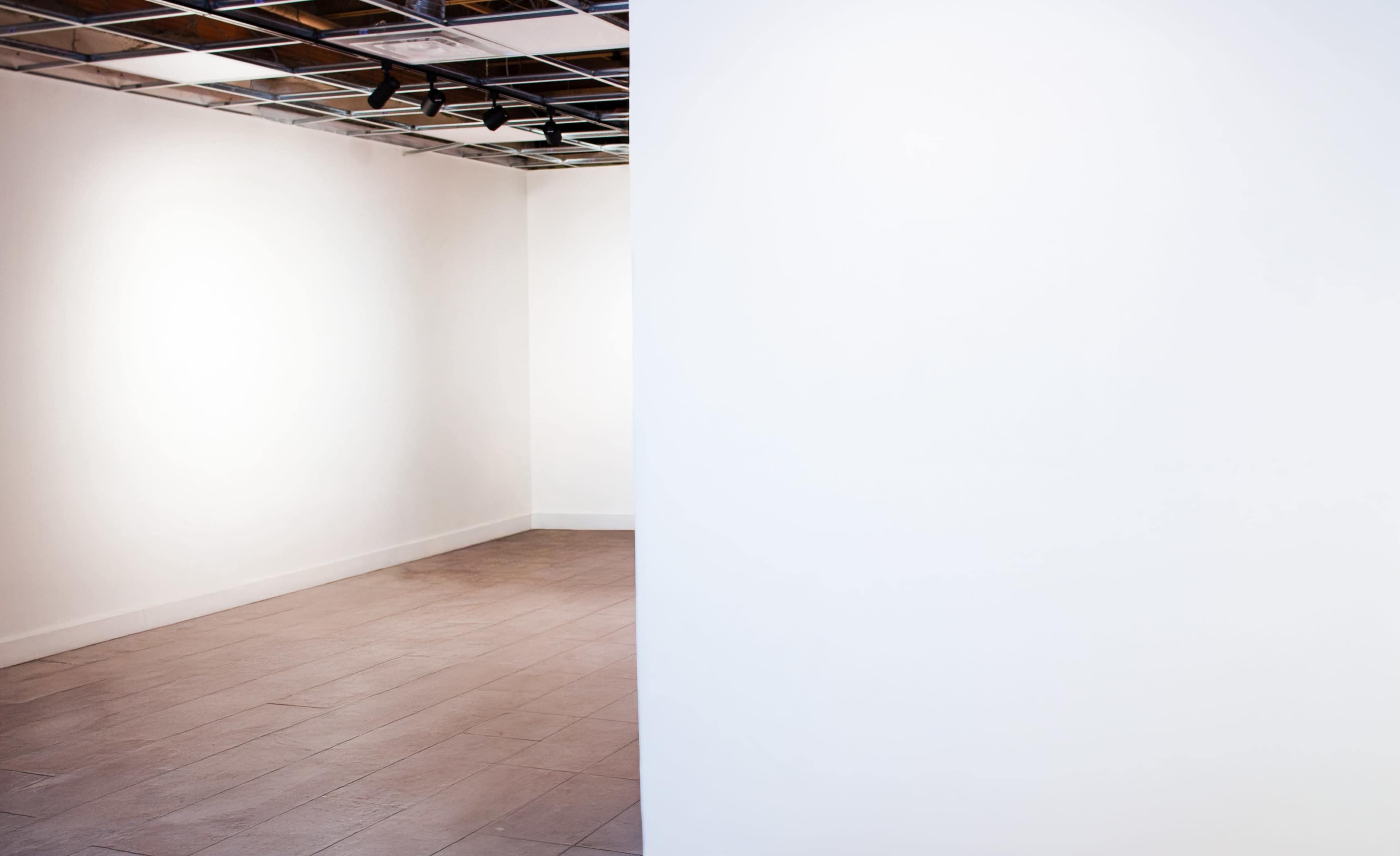 The image shows a spacious, mostly empty room with white walls and a tiled floor.