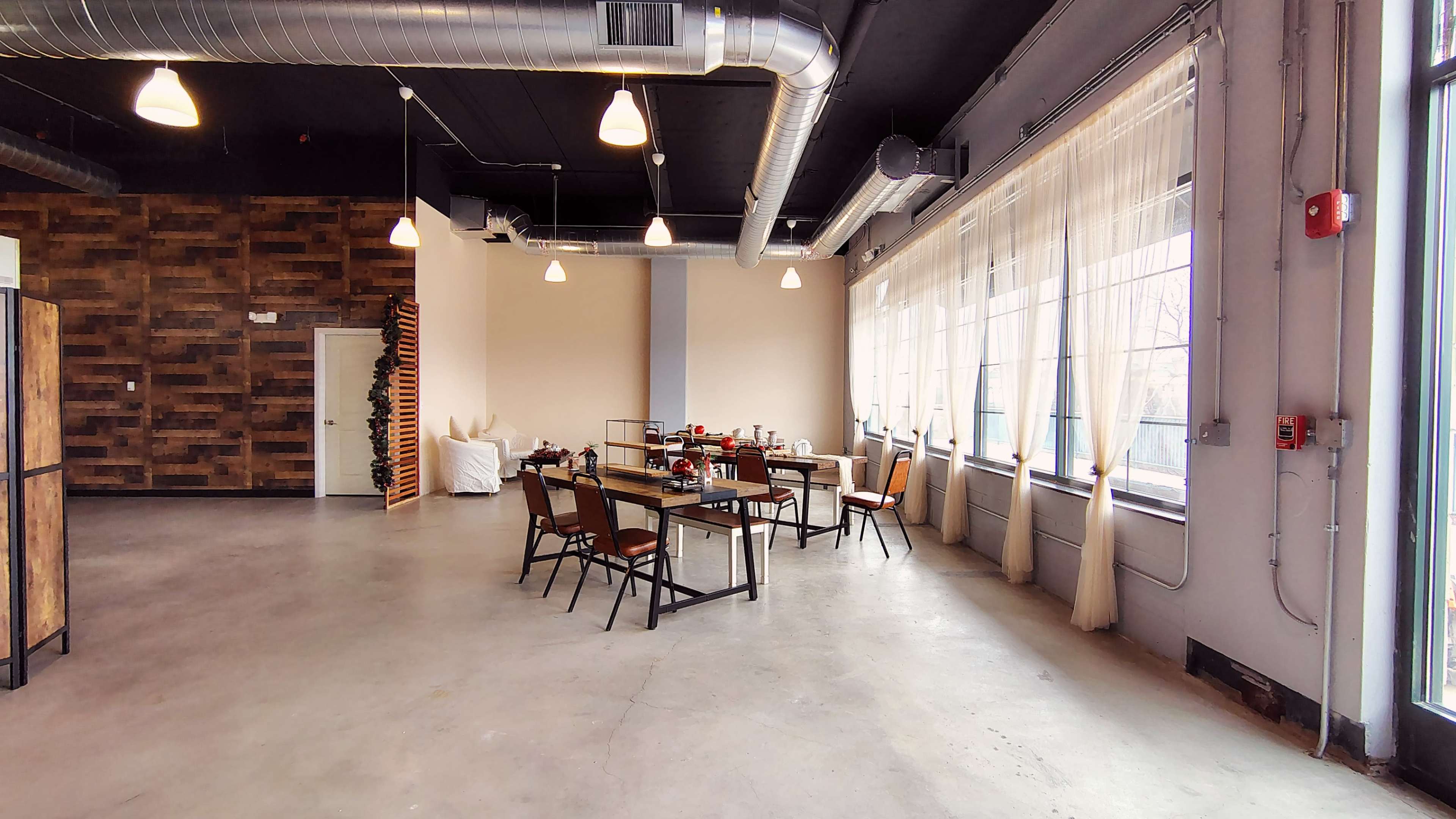 The image shows a spacious, modern interior of a dining area with large windows, wooden accents, and a table set for a meal.