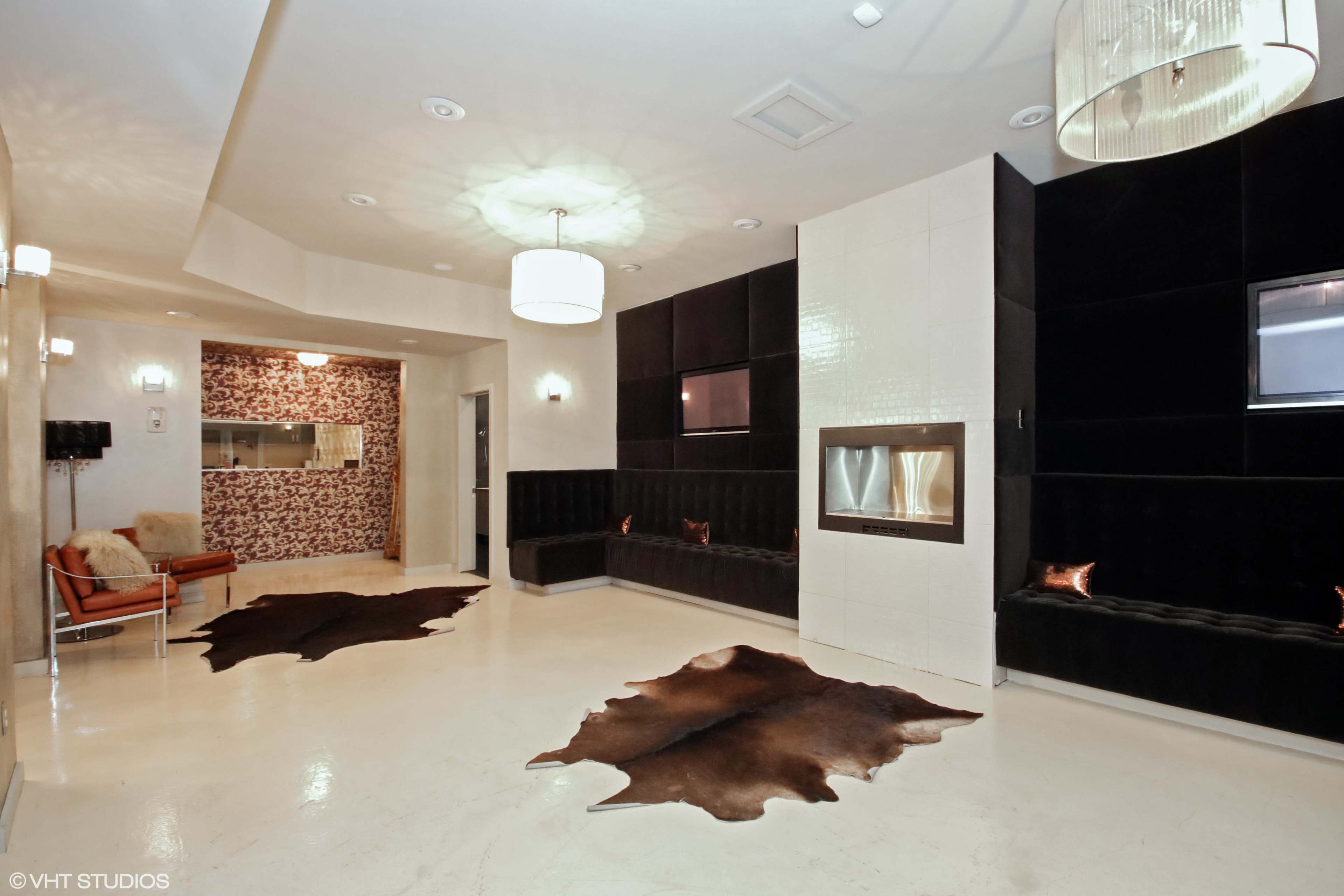 The room features a modern interior with black walls, a fireplace, seating areas, and decorative cowhide rugs on the floor.