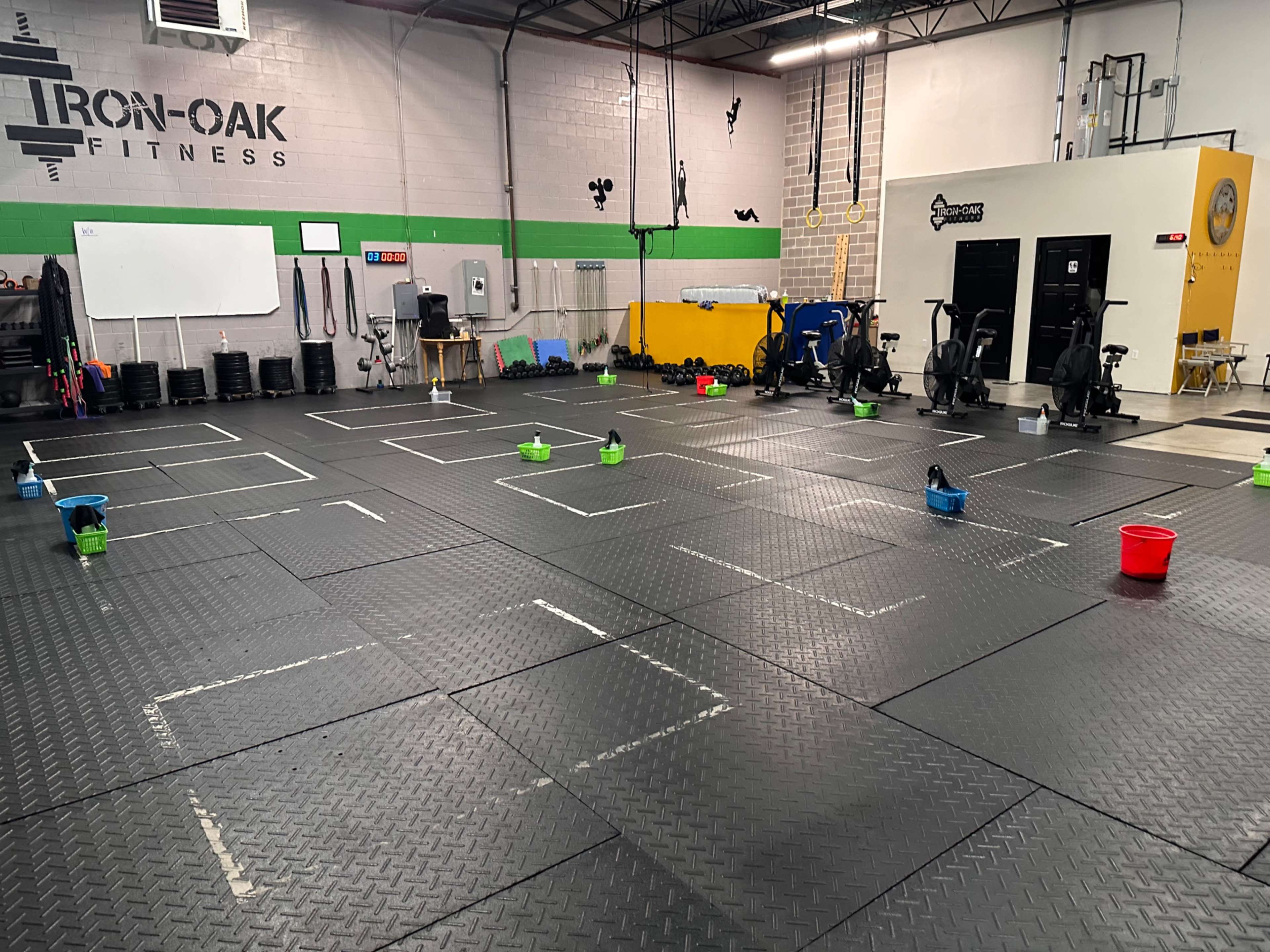 A spacious gym floor with marked boxes and buckets in a fitness facility.