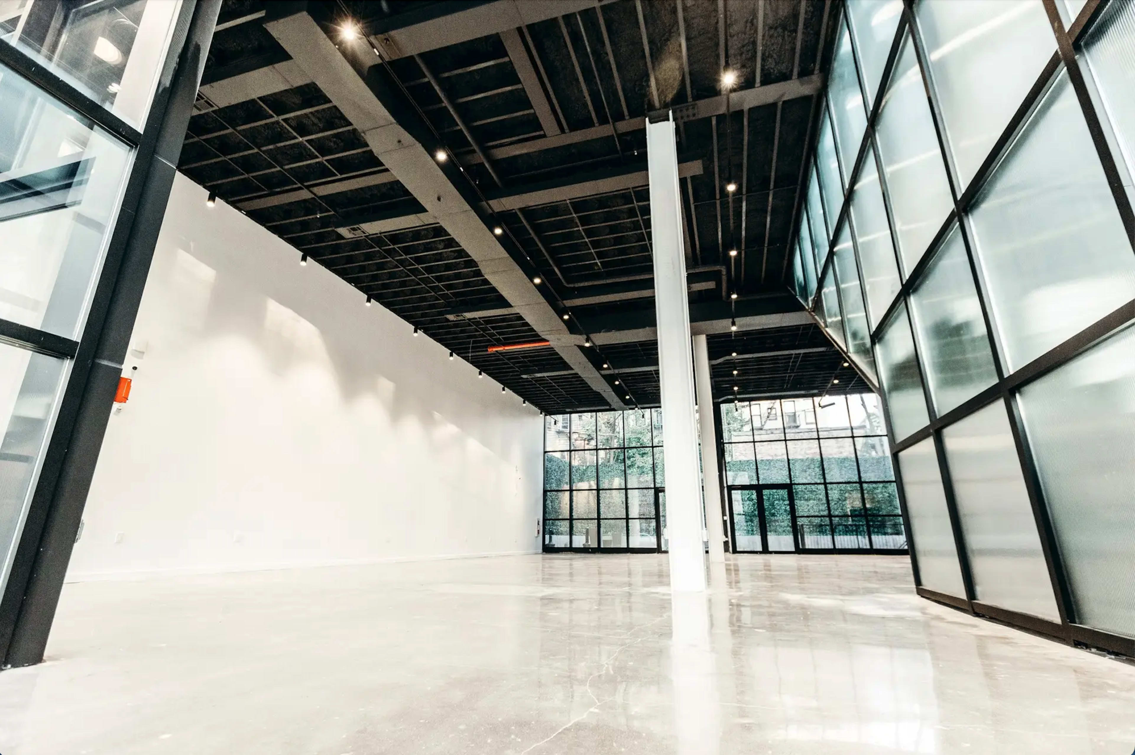 An empty commercial space with high ceilings, large windows, and polished concrete floors.