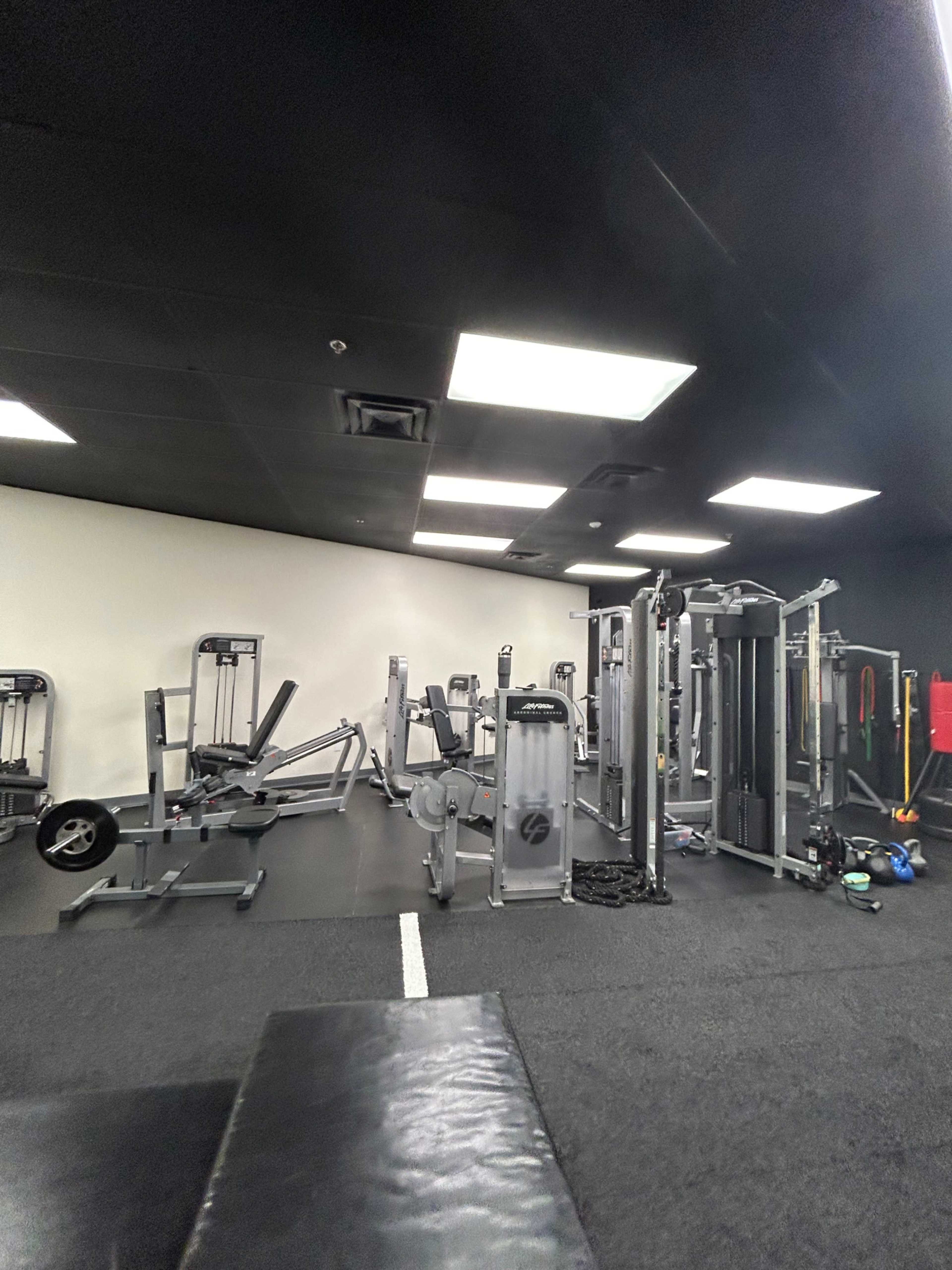 A gym interior with various fitness equipment arranged in a well-lit space.