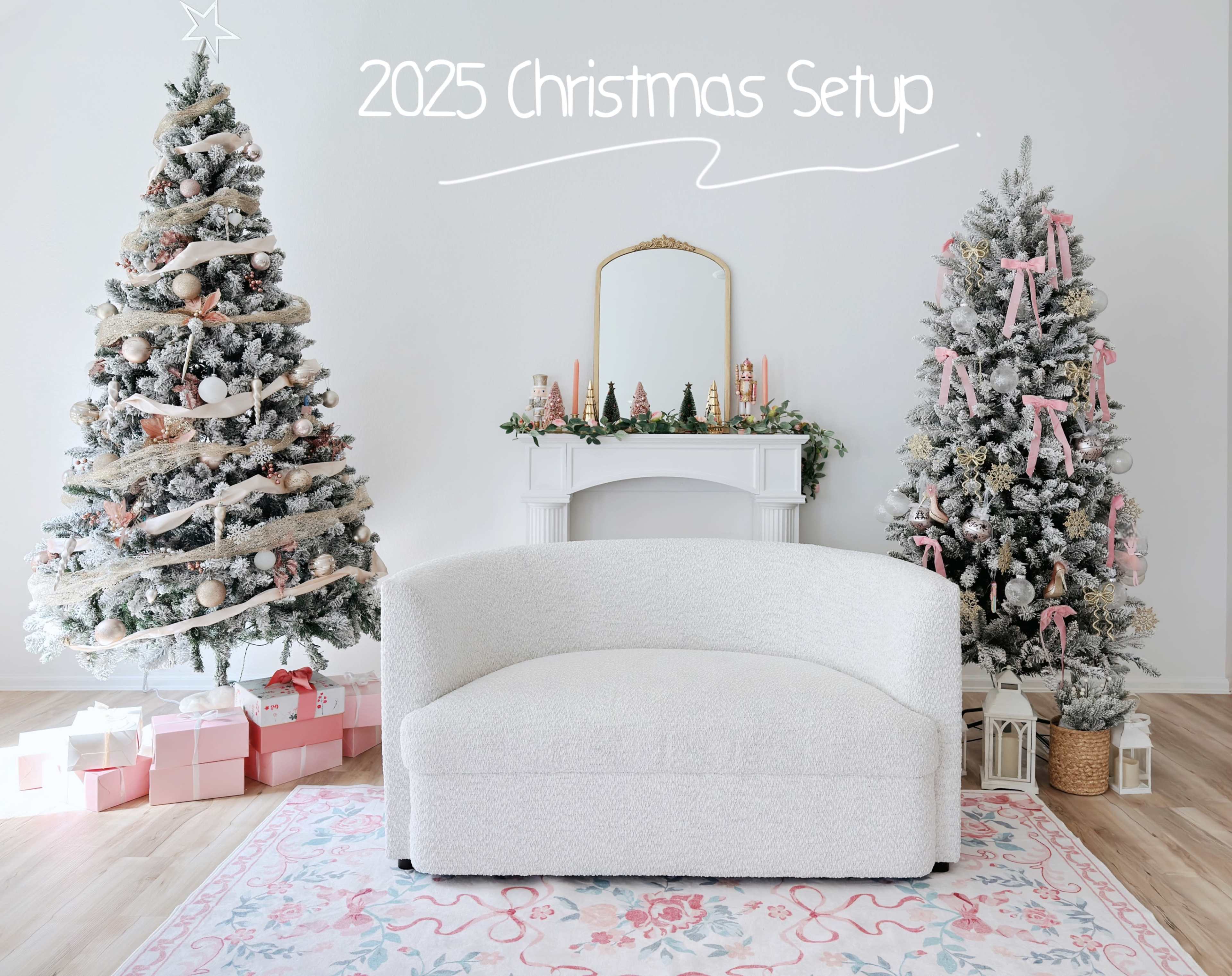 A white, modern couch is positioned in front of two decorated Christmas trees and a mantle adorned with festive decorations, all set against a light-colored wall.