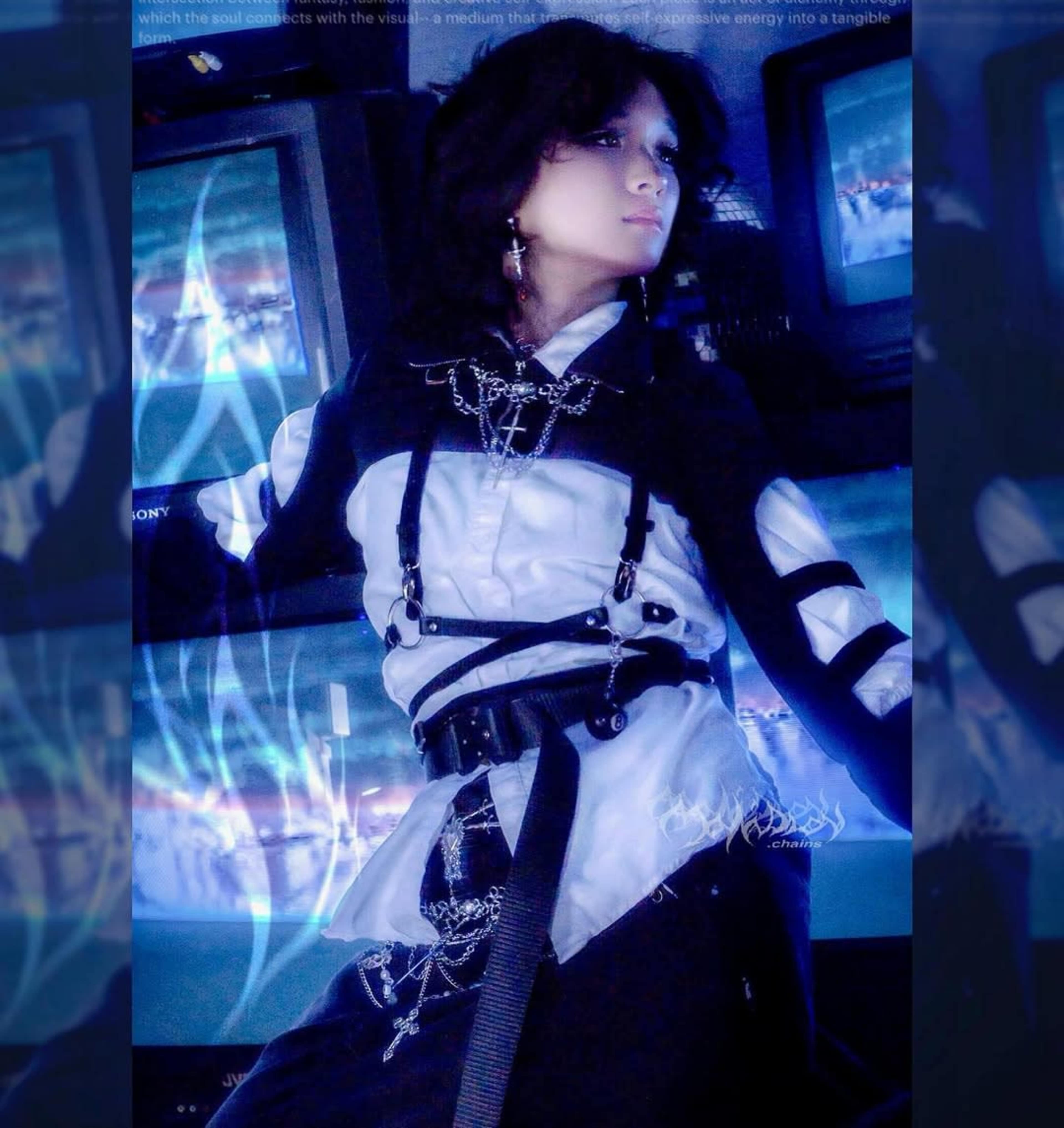 A person in a stylish outfit with black and white elements poses in front of multiple television screens.