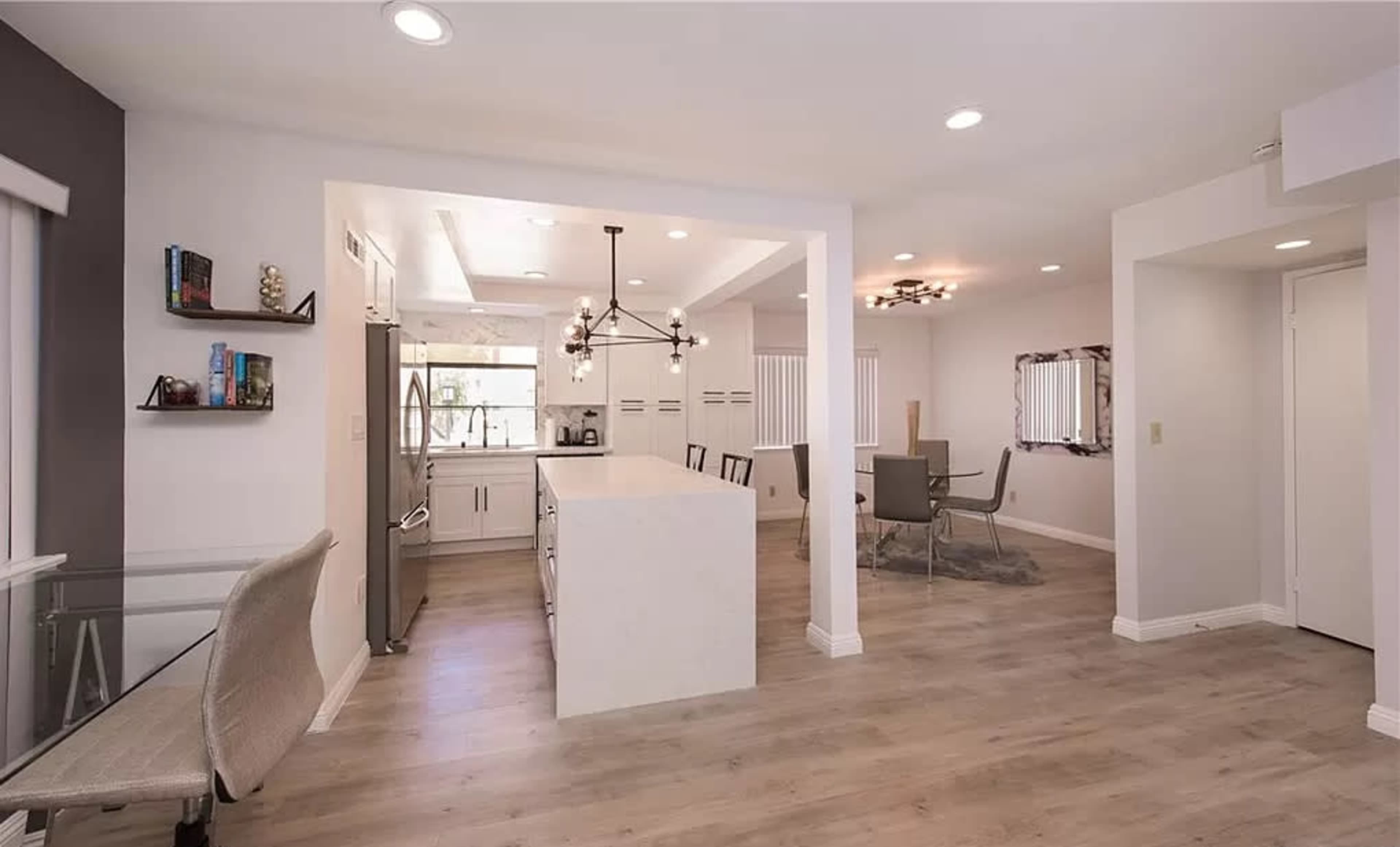 An open-concept kitchen and dining area with a modern design, featuring light wood flooring and a central island.