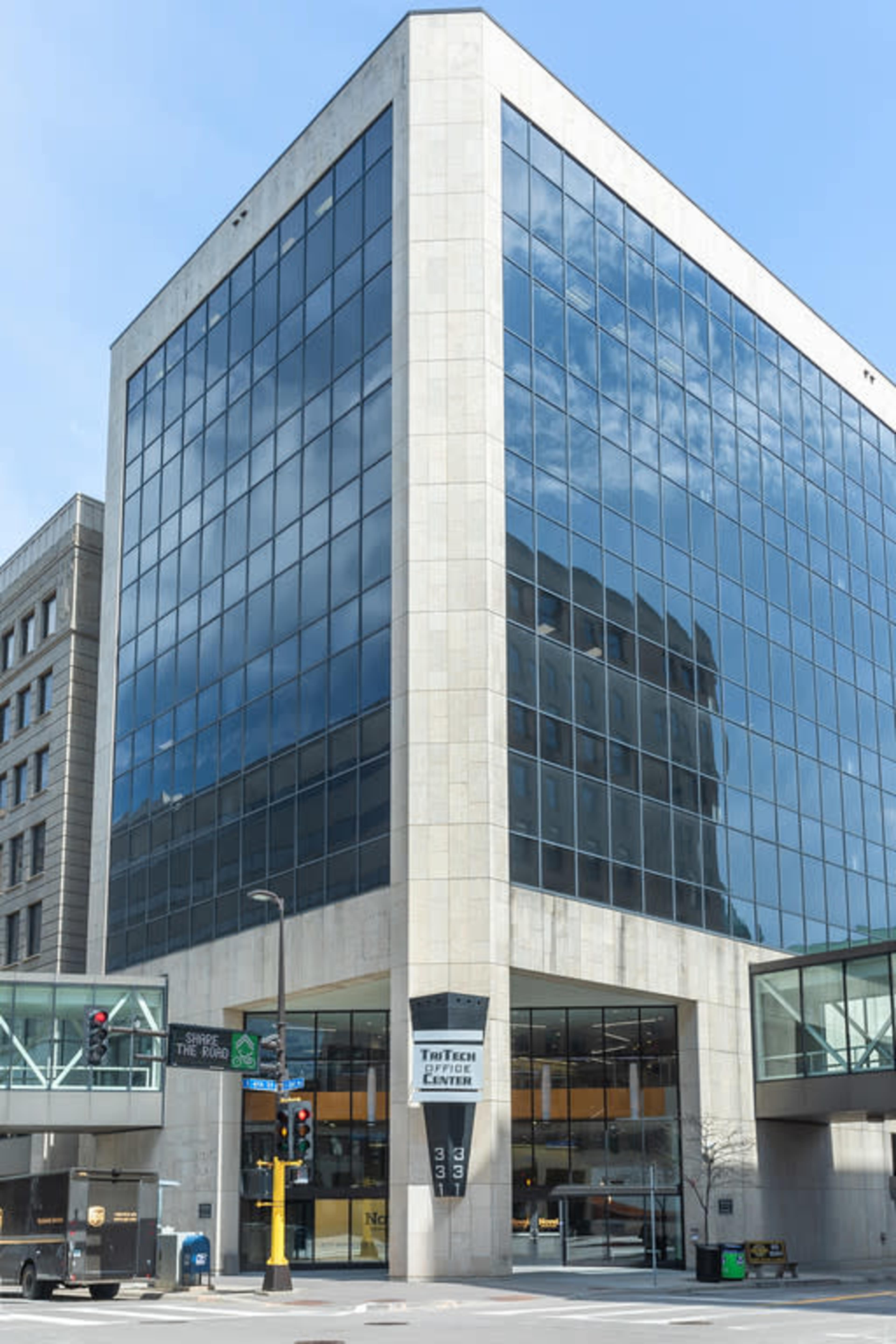 The image shows a modern glass and concrete building with a large façade, prominently featuring the "Tech Center" sign at the entrance.