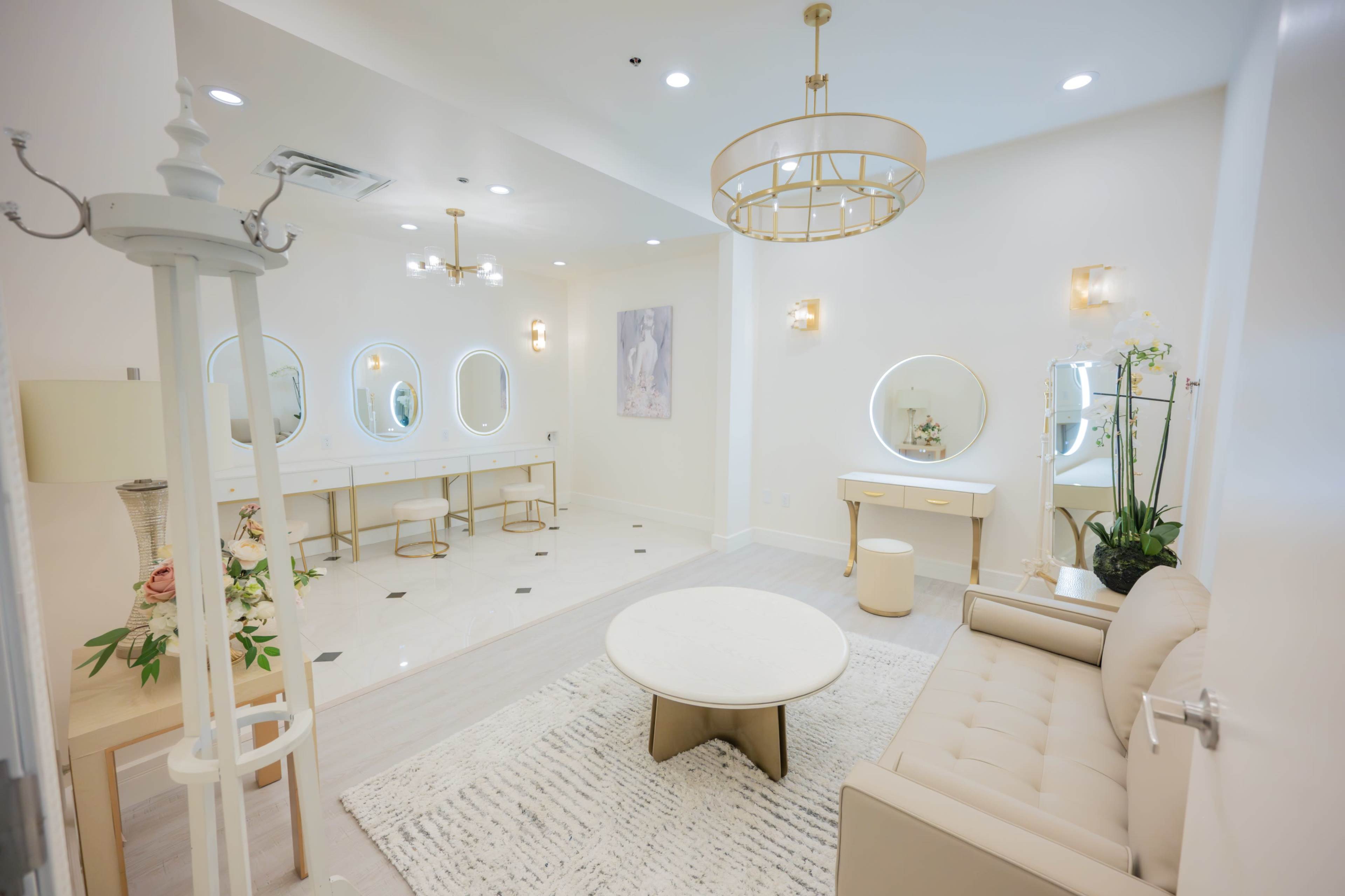 The image shows a well-lit, modern dressing room with a sofa, circular mirrors, and a neatly arranged seating area.