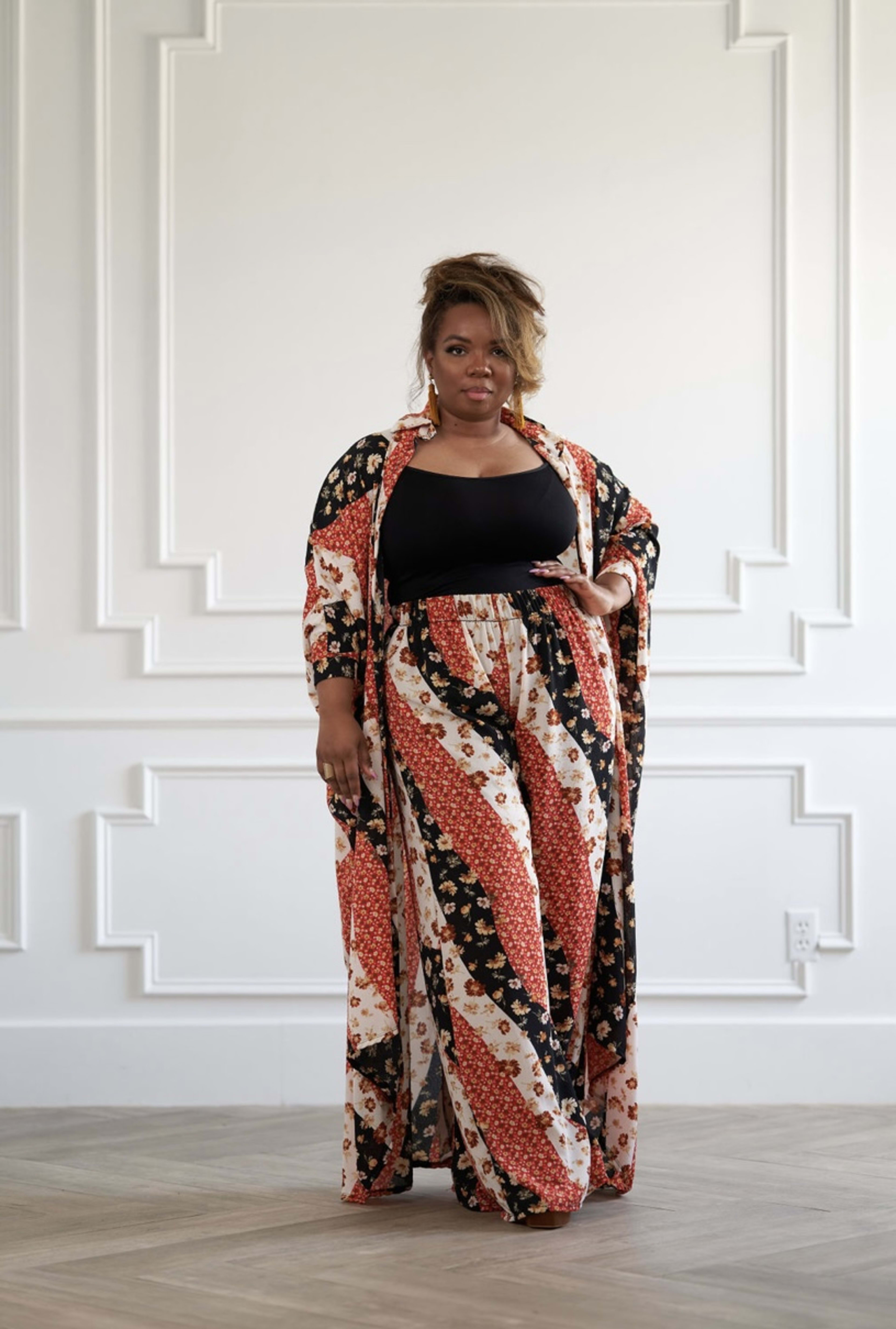 A fashion model posing in front of a white wall.