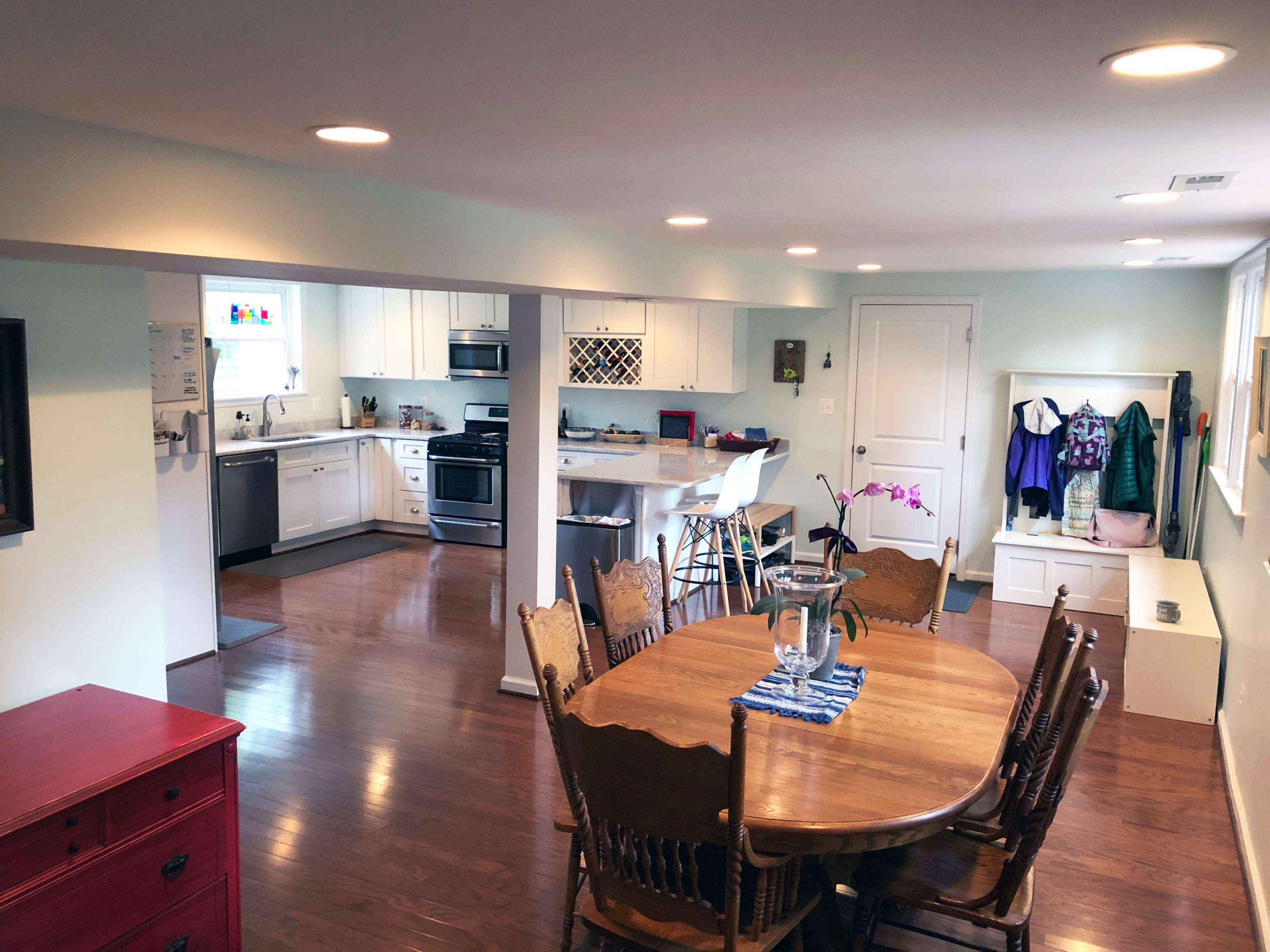 A brightly lit open-concept kitchen and dining area featuring a wooden dining table, beige walls, and modern appliances.