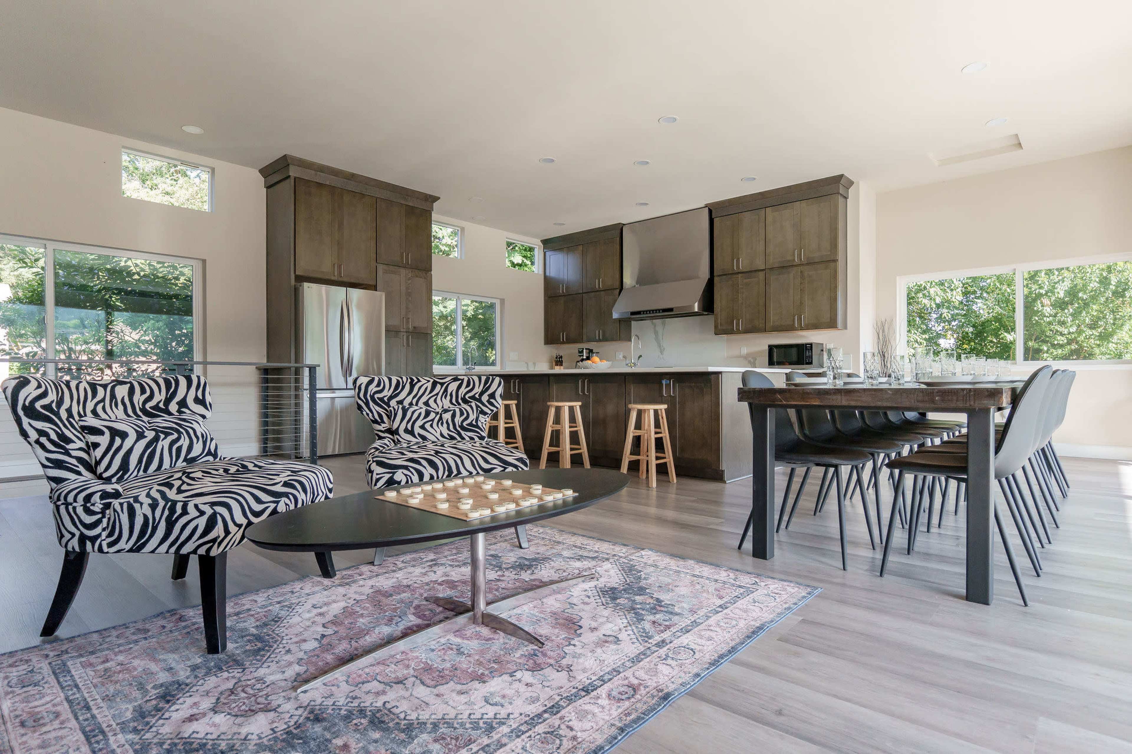 A modern kitchen and living area feature sleek cabinetry, zebra-print chairs, and a large dining table.