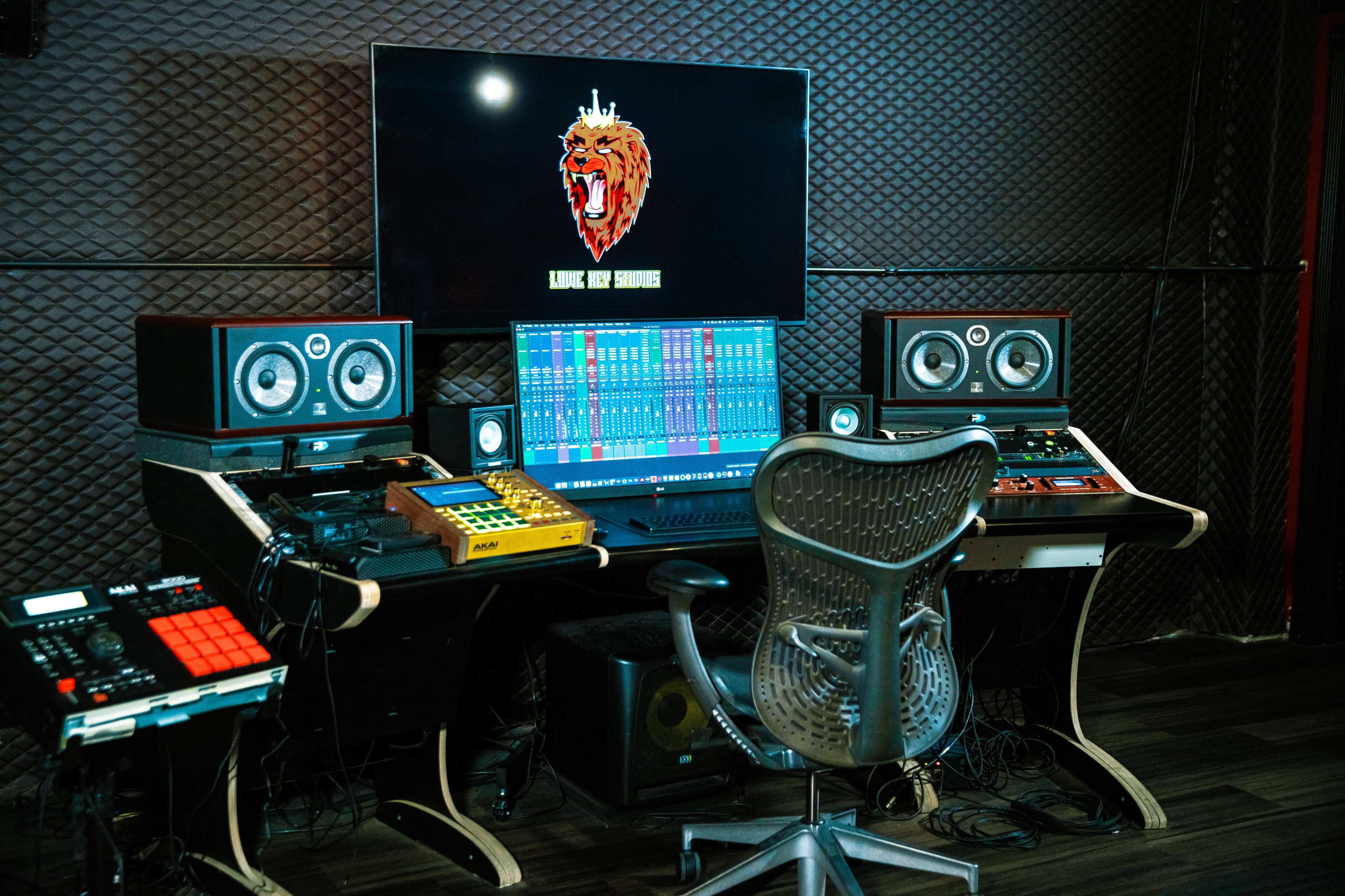 A sound studio with multiple audio equipment, computer monitors, and a central workstation chair.