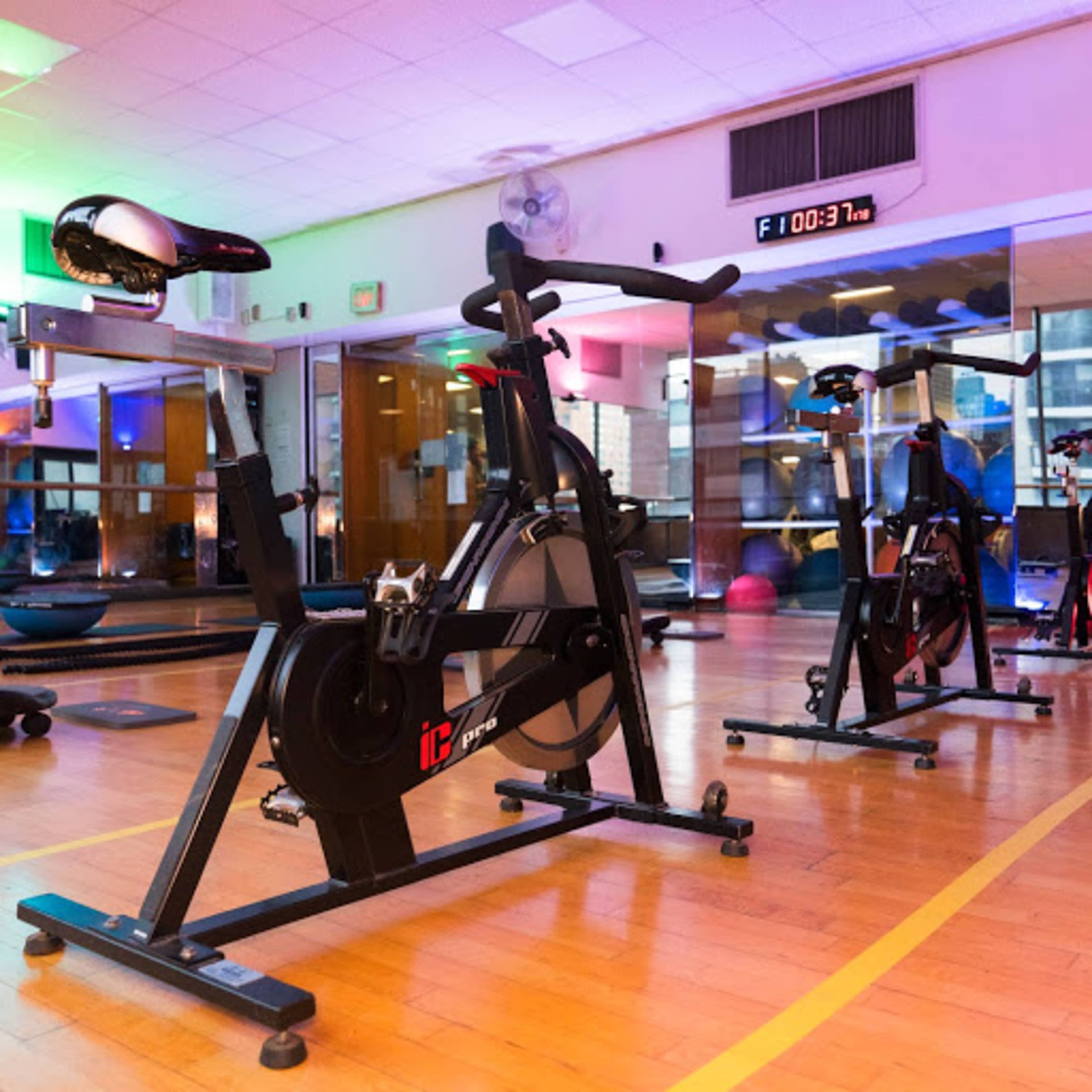 A well-lit indoor cycling studio equipped with stationary bikes and exercise equipment.