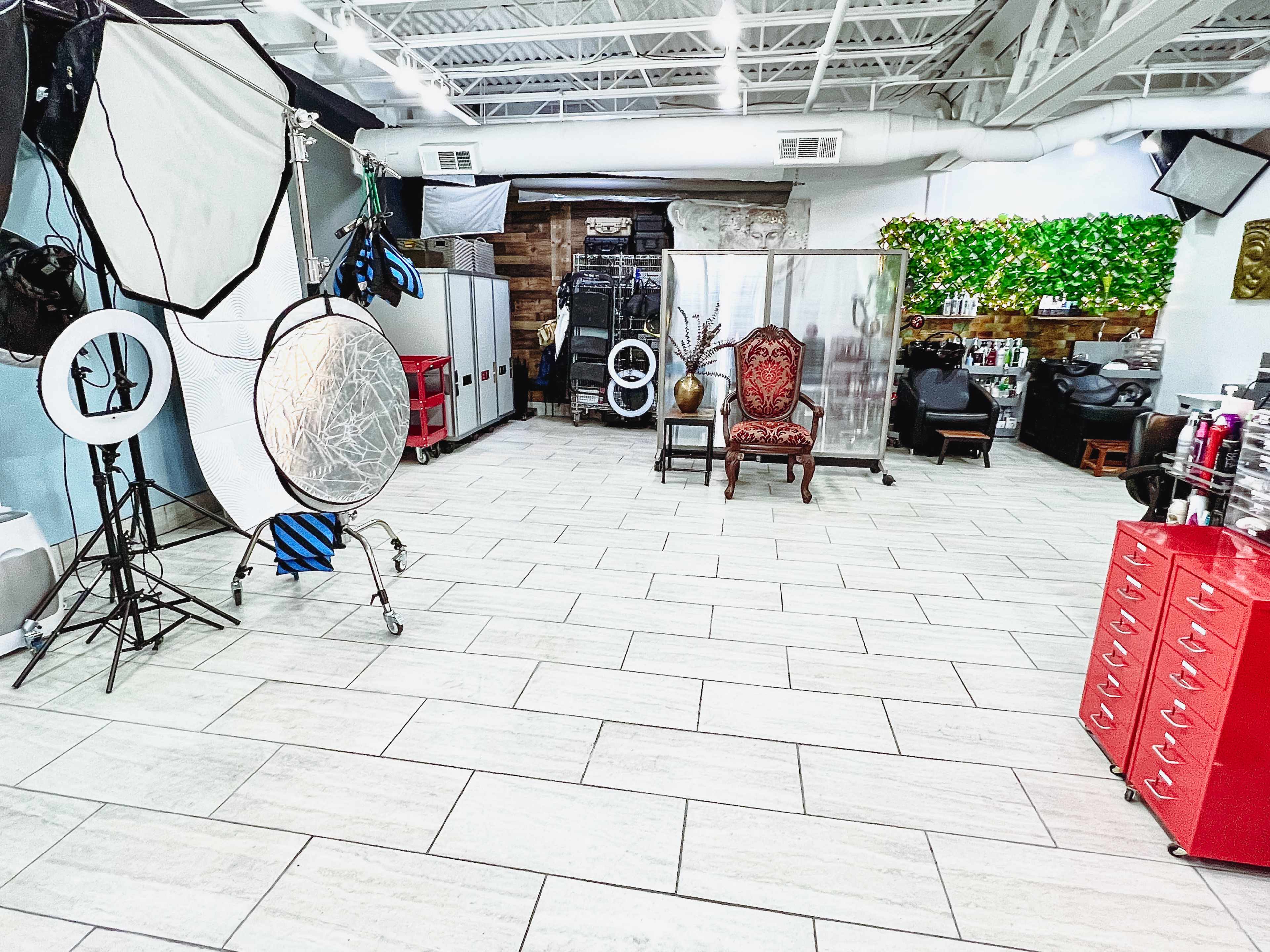 A spacious salon interior with a mix of styling equipment, a large mirror, and a decorative antique chair.
