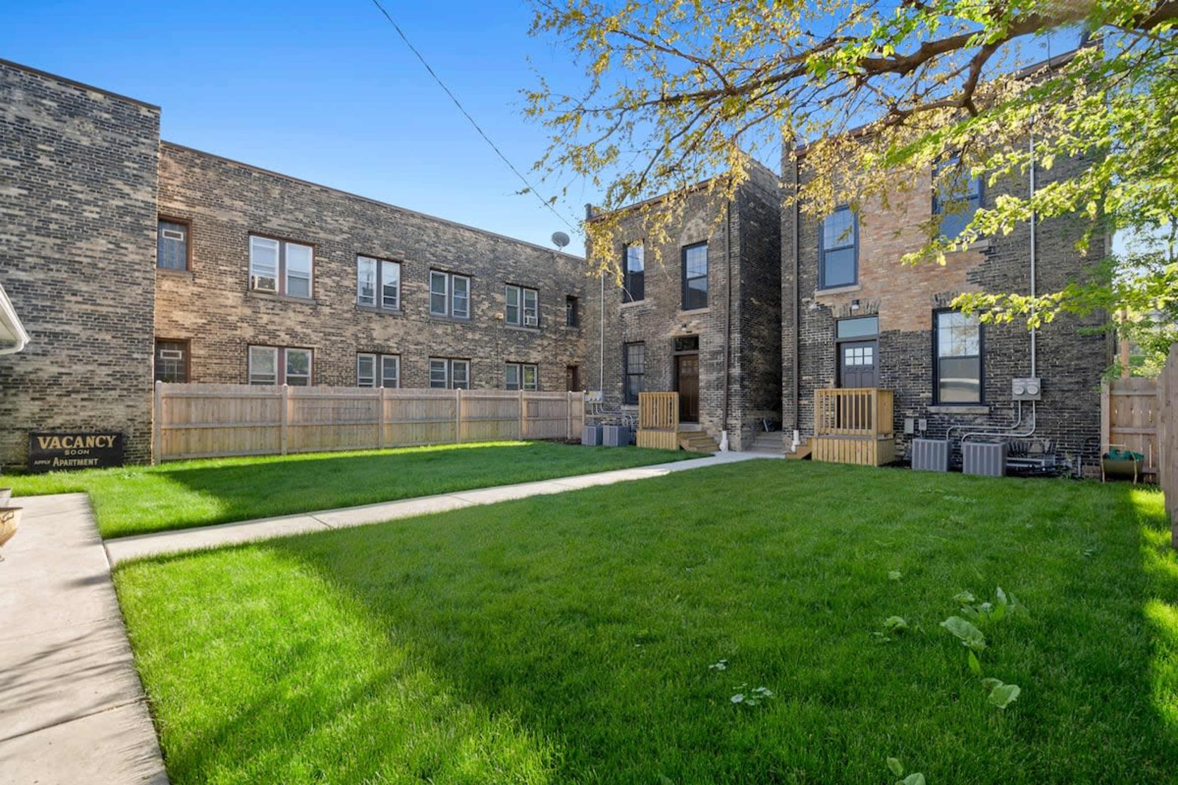 A two-story brick building complex with a grassy courtyard and a "Vacancy" sign.
