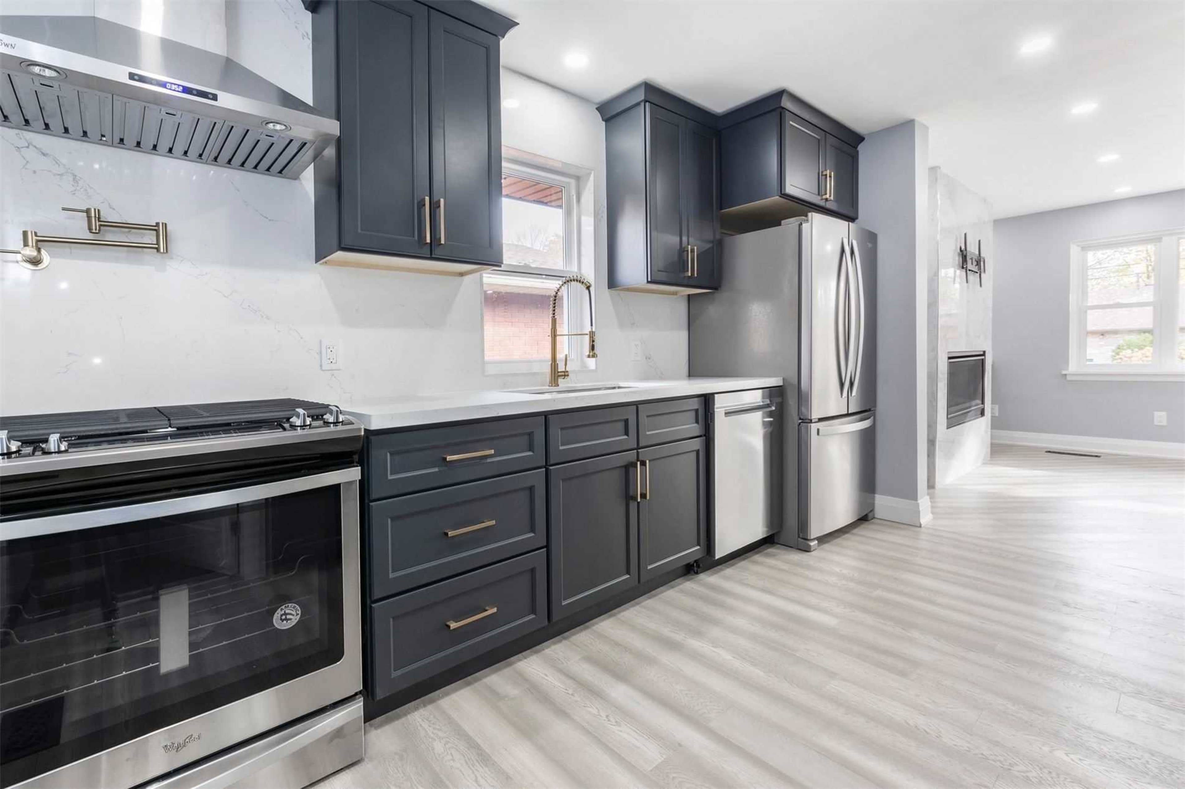The image shows a modern kitchen with dark cabinetry, stainless steel appliances, and a spacious countertop.