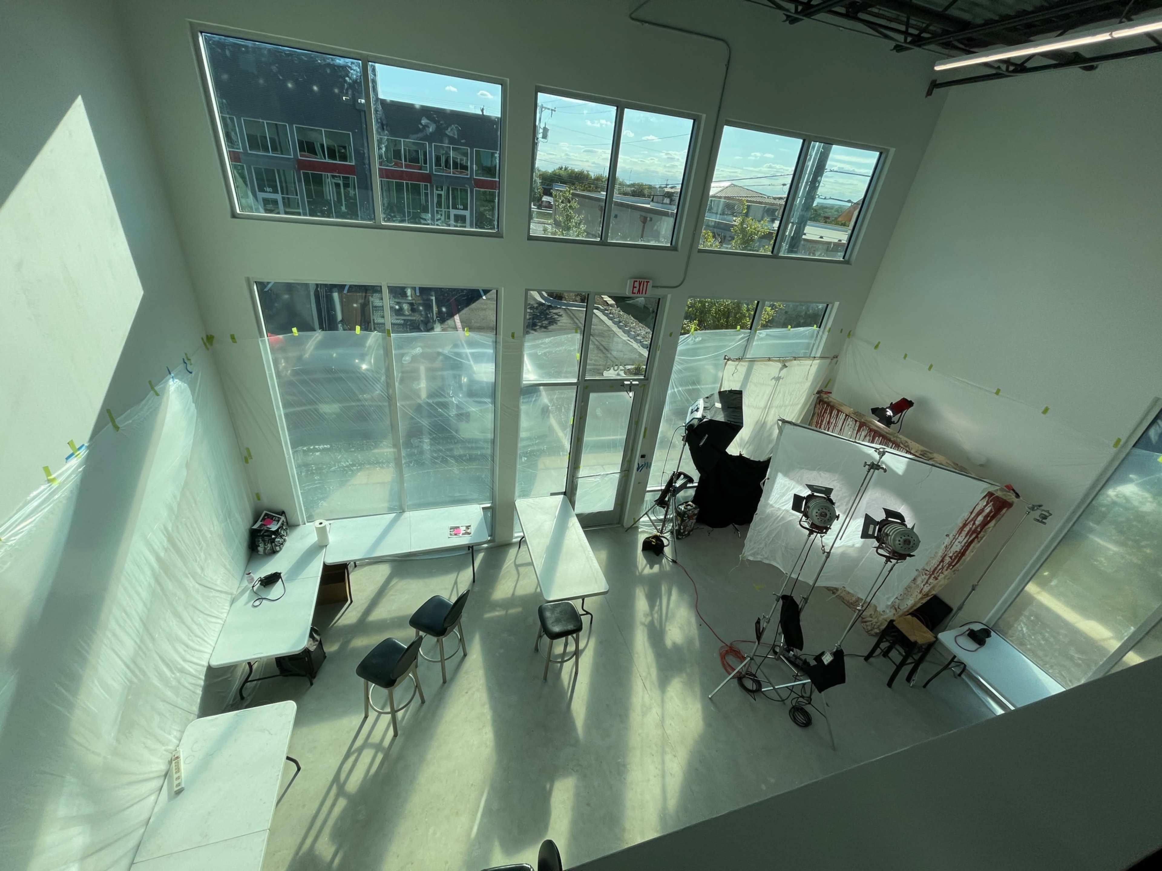 A spacious, well-lit studio with tables and chairs, large windows, and a backdrop setup for photography.