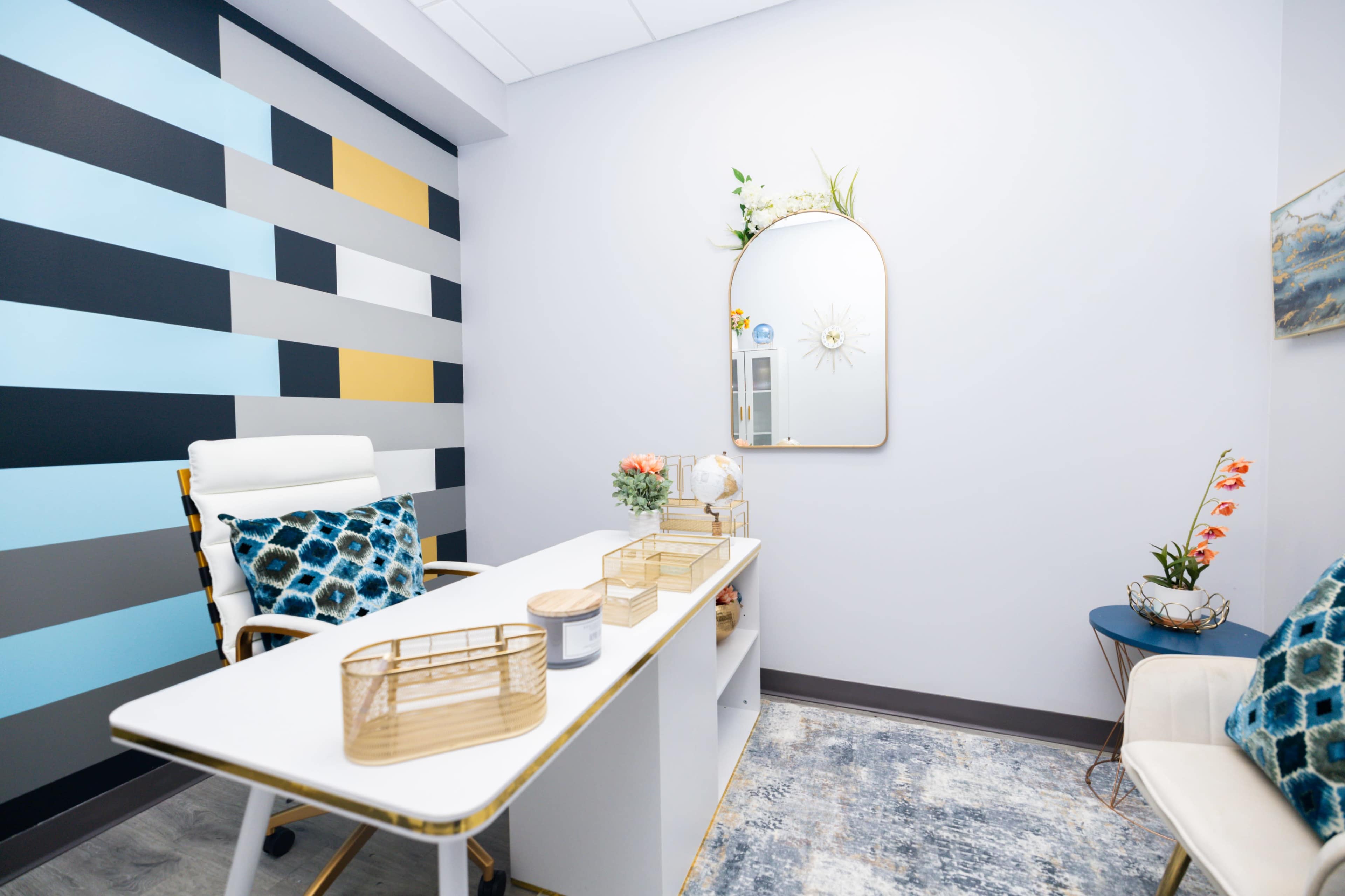 A modern office space features a minimalist desk, a round mirror, and patterned walls in blue and gray tones.